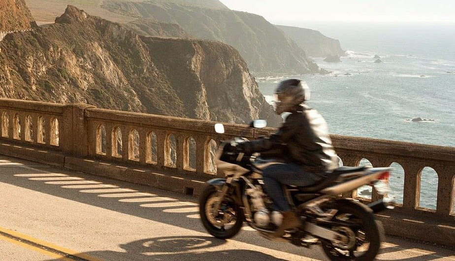 Man on motorcycle going over bridge in Big Sur