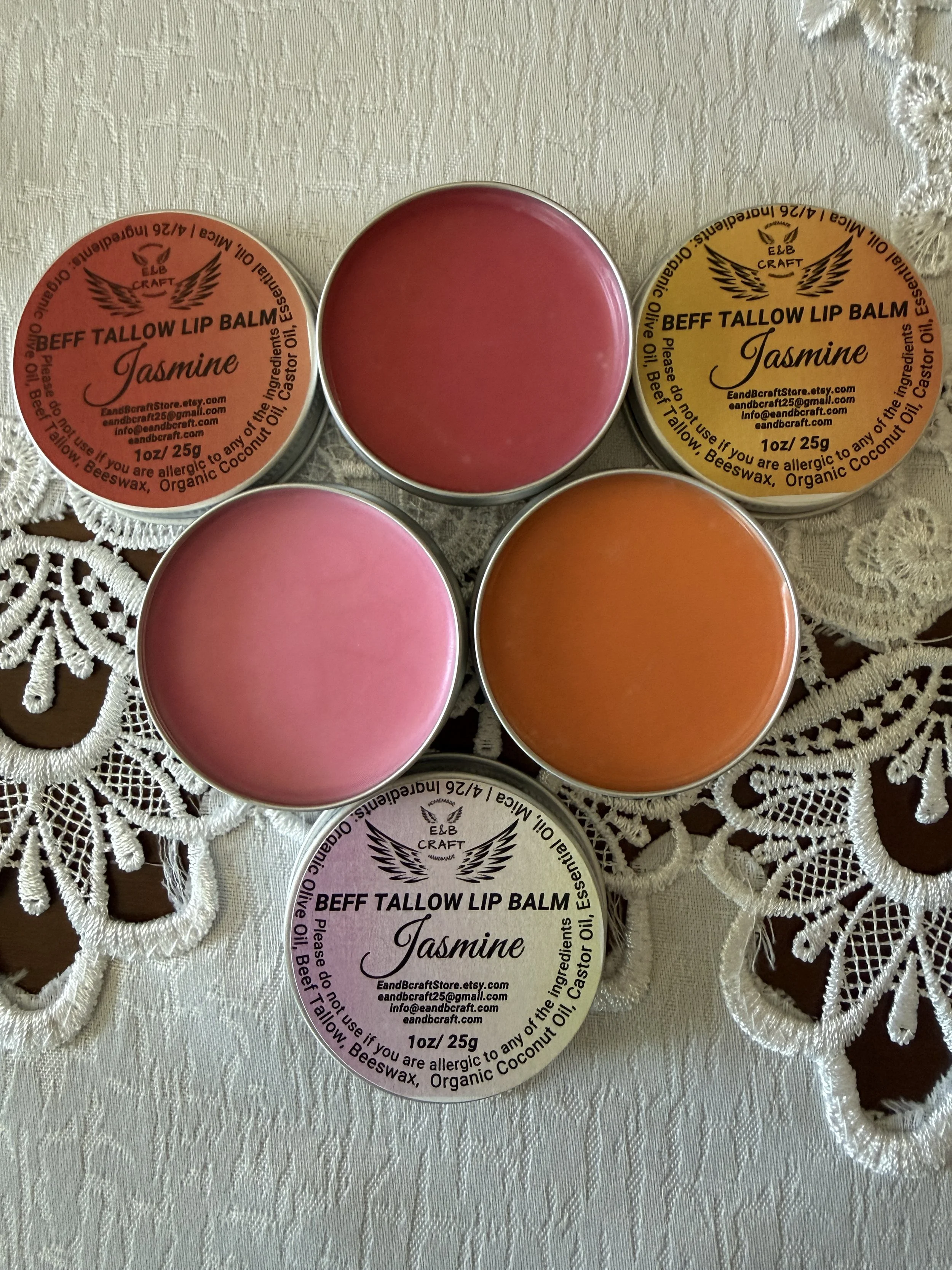 Red orange pink beef tallow lip balm tins arranged natural skincare collection