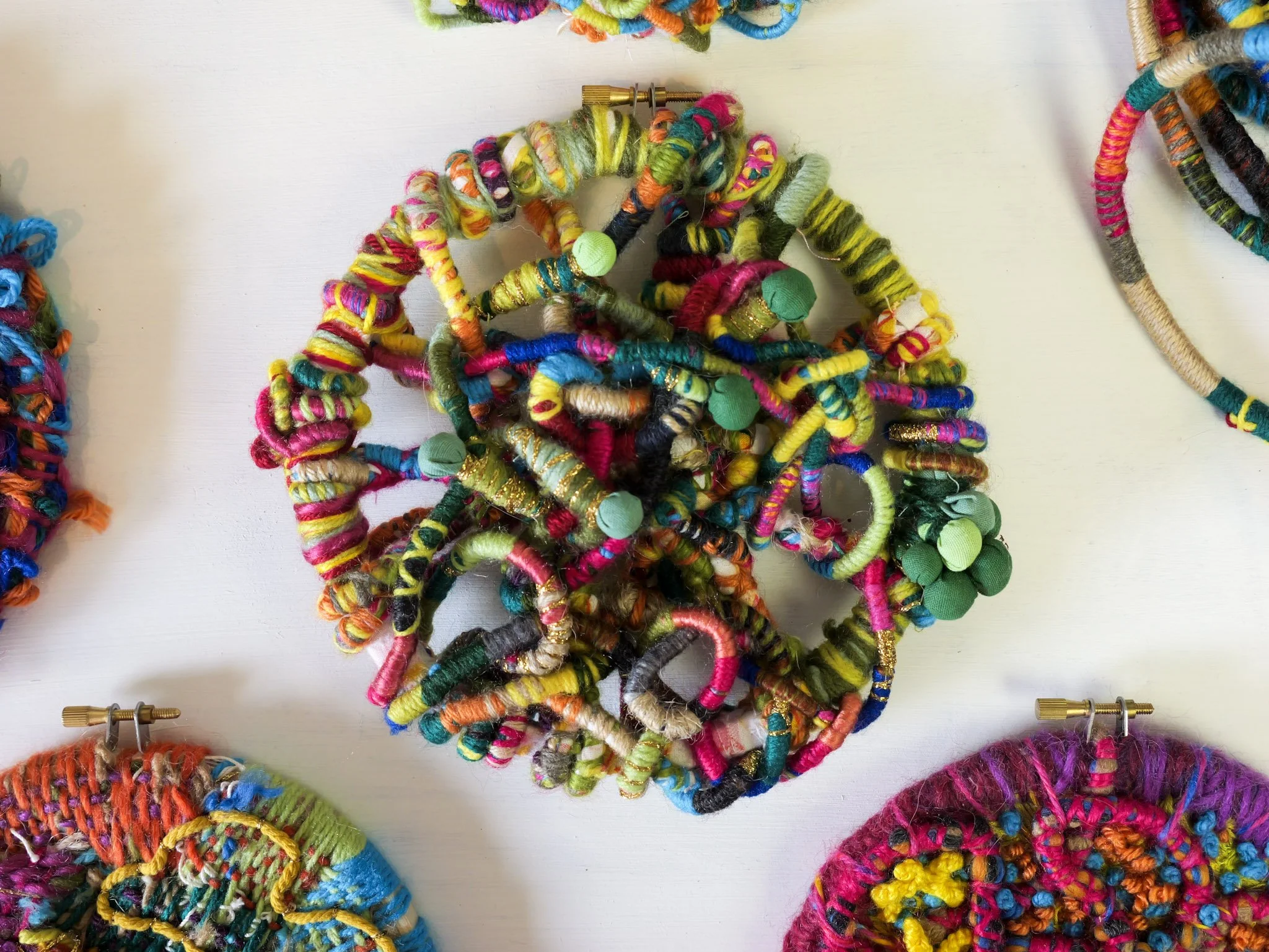 Colorful handmade fabric and yarn jewelry or accessories on display.