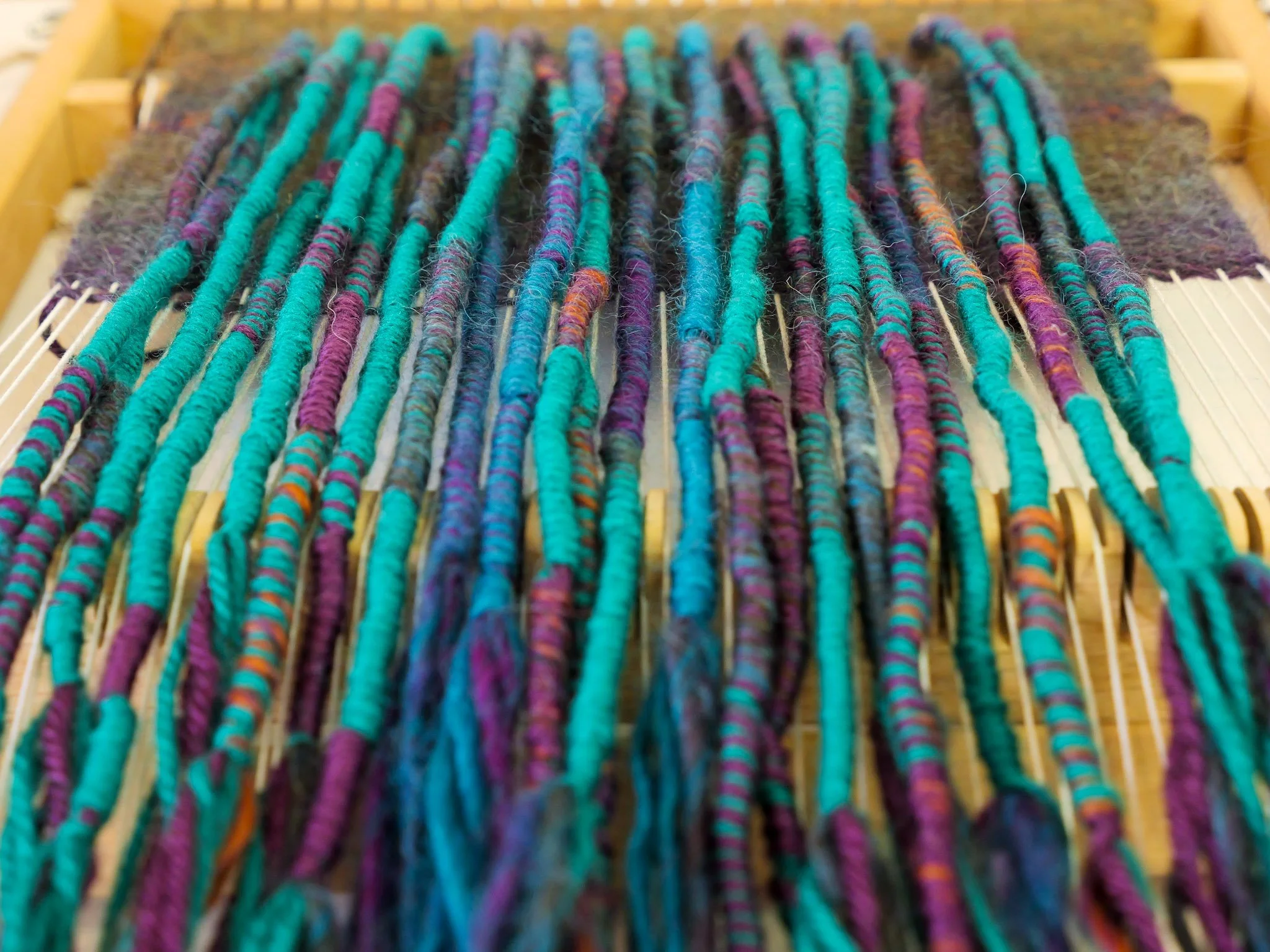 Close-up view of multicolored yarn strands on a weaving loom.