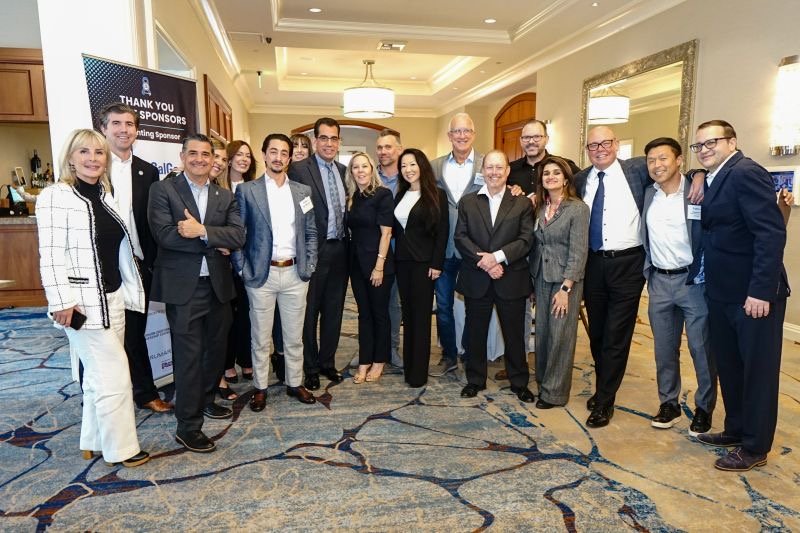 A group of diverse professionals dressed in business attire standing together in a conference room, smiling for a photo.