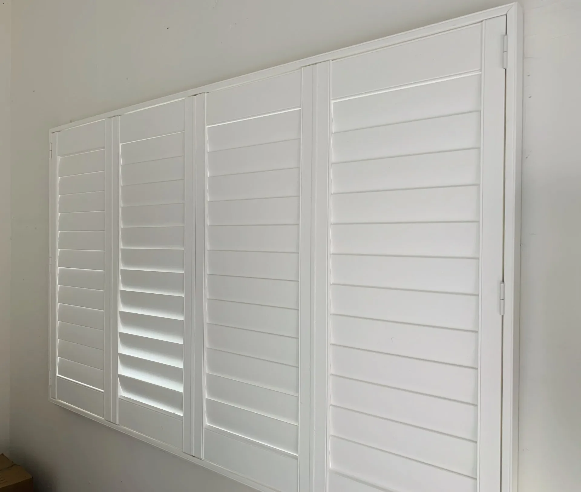 A white wooden closet with multiple panels and horizontal slats, mounted on a white wall.