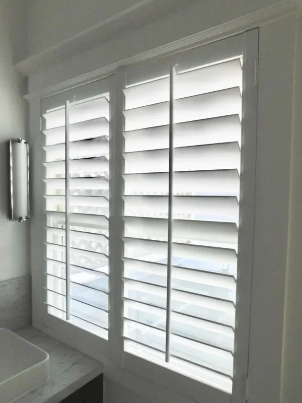Window with white plantation shutters in a bright room.
