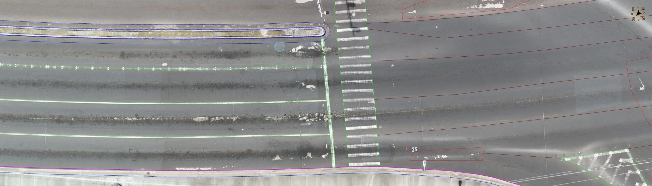 Aerial view of a crosswalk at an intersection on a city street showing multiple colored lines and markings for pavement analysis or mapping.