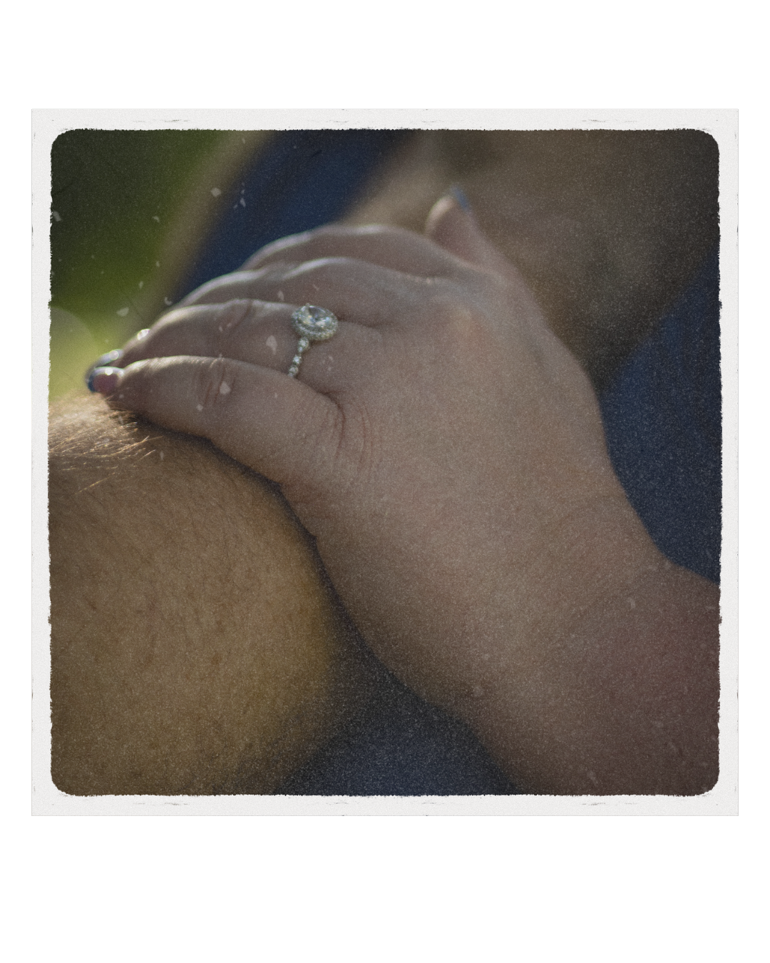 Close-up of a person’s hand with a diamond ring resting on someone's chest.