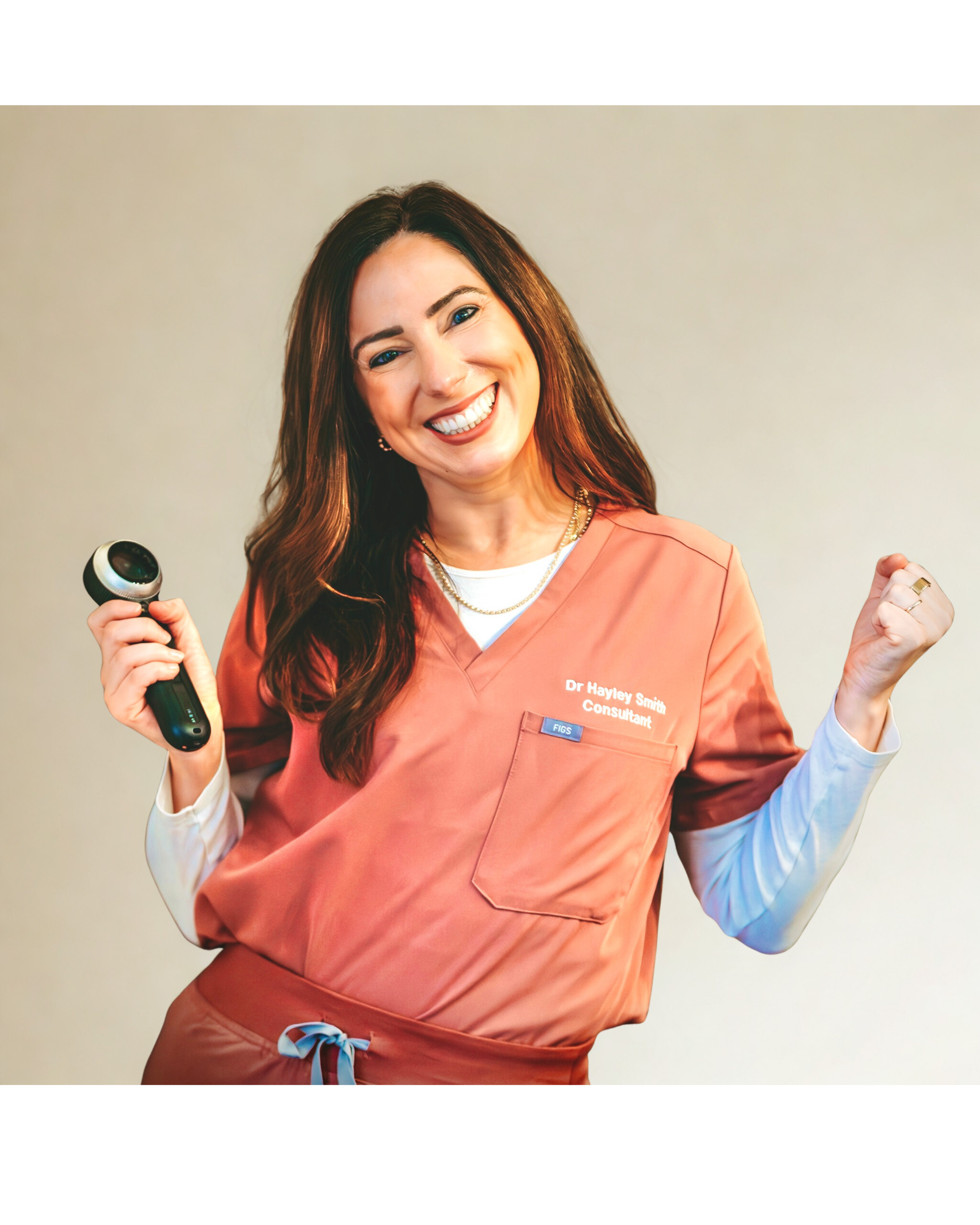 A smiling woman in medical scrubs holding a reflex hammer, celebrating with her fist clenched.