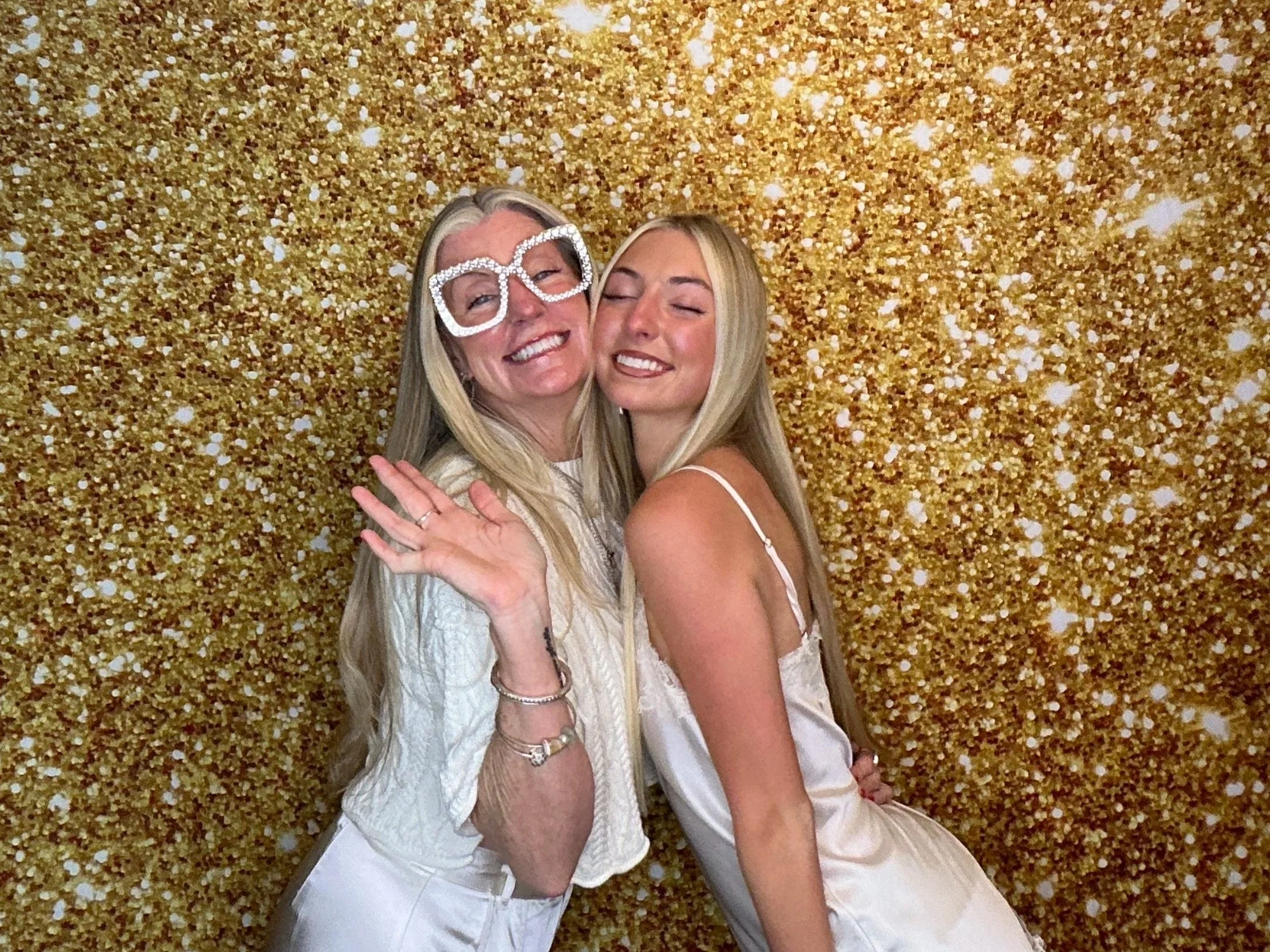 Two guests capturing fun memories with a gold glitter backdrop at a Pop & Pose Photo Booth. Our premium Photo Booth rentals are perfect for weddings, bridal showers, birthday parties, and special events across Central Florida.