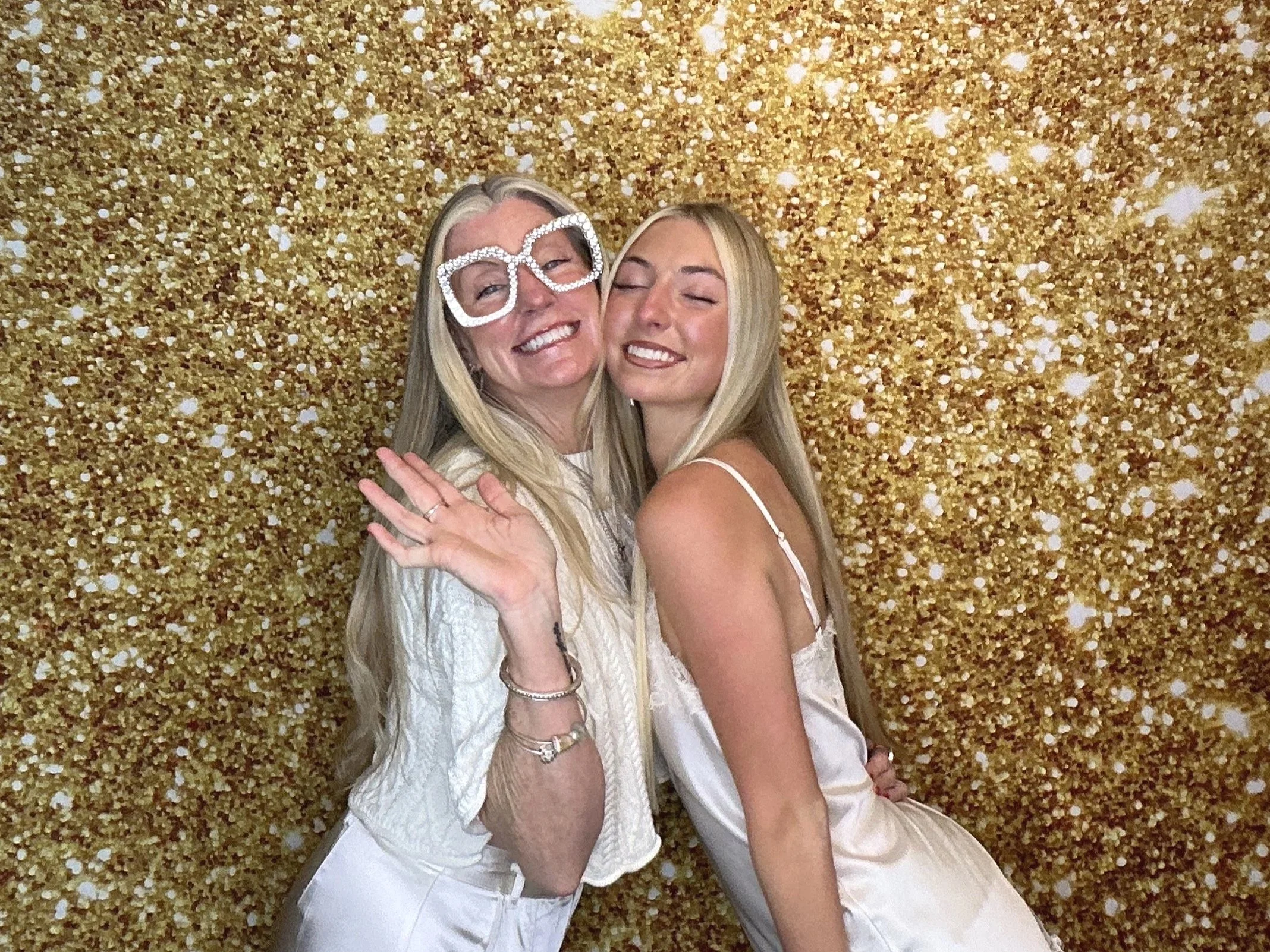 Two guests posing in front of a gold glitter backdrop at a Pop & Pose Events Photo Booth in Lake Mary, Florida.