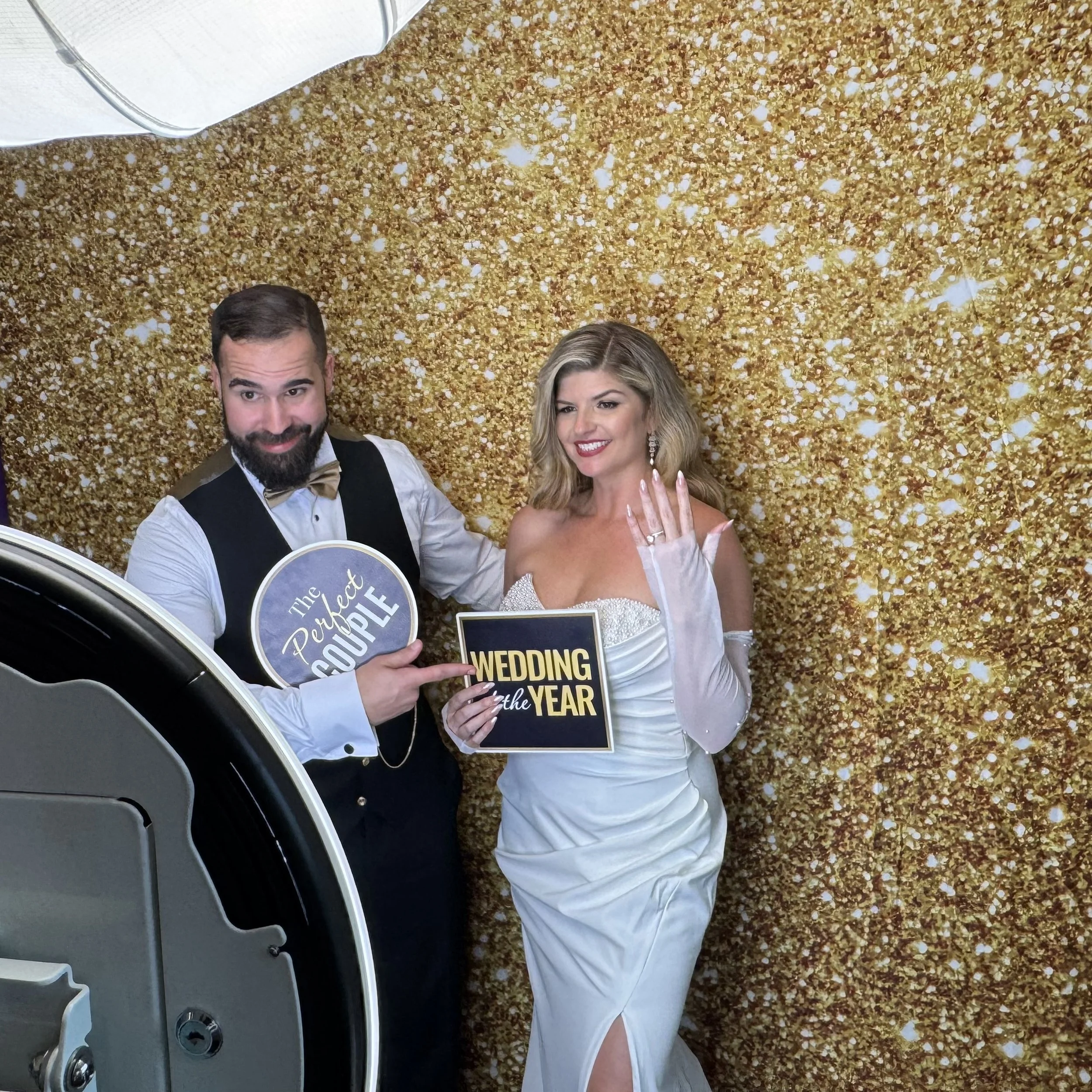 Bride and groom enjoying a modern Photo Booth with a gold glitter backdrop at a wedding in Orlando, Florida.