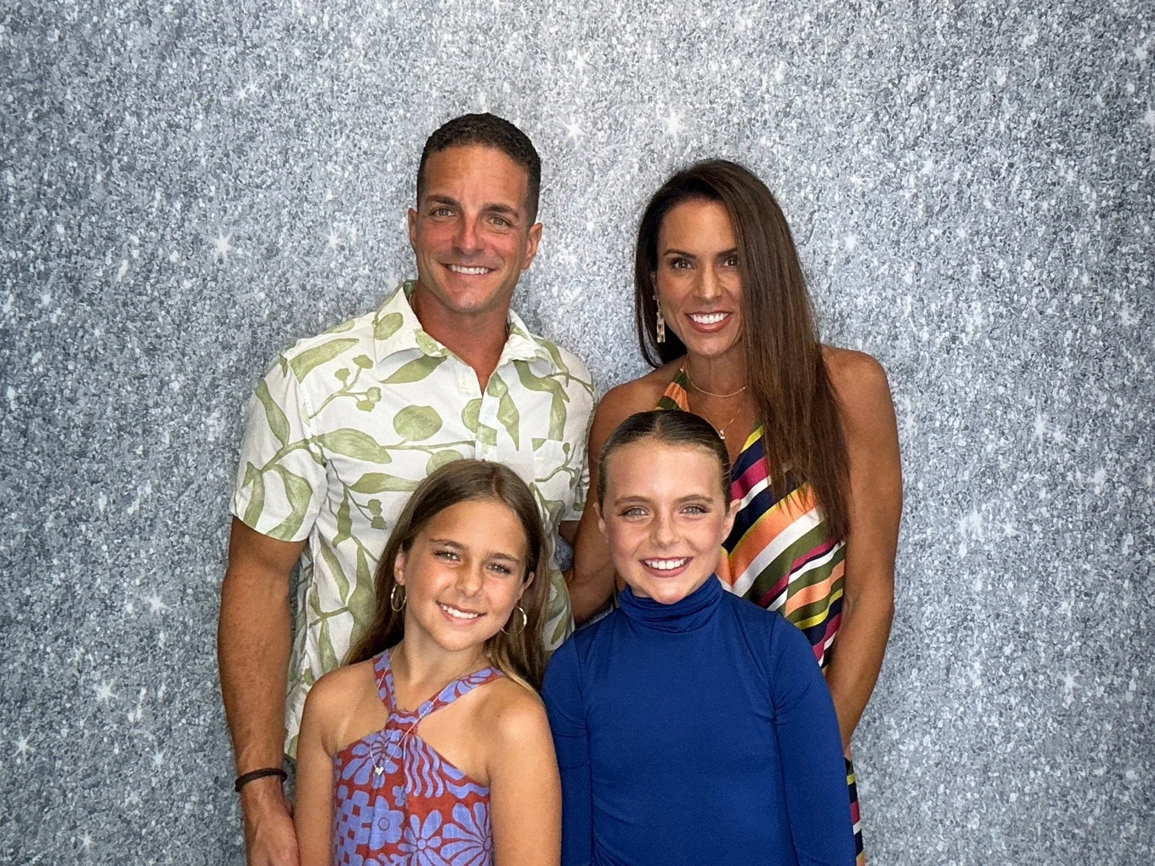 Family posing together at a Pop & Pose Photo Booth with silver shimmer backdrop during a special celebration. Our Photo Booth rentals create unforgettable memories for birthdays, family reunions, and private events throughout Winter Springs & Orlando