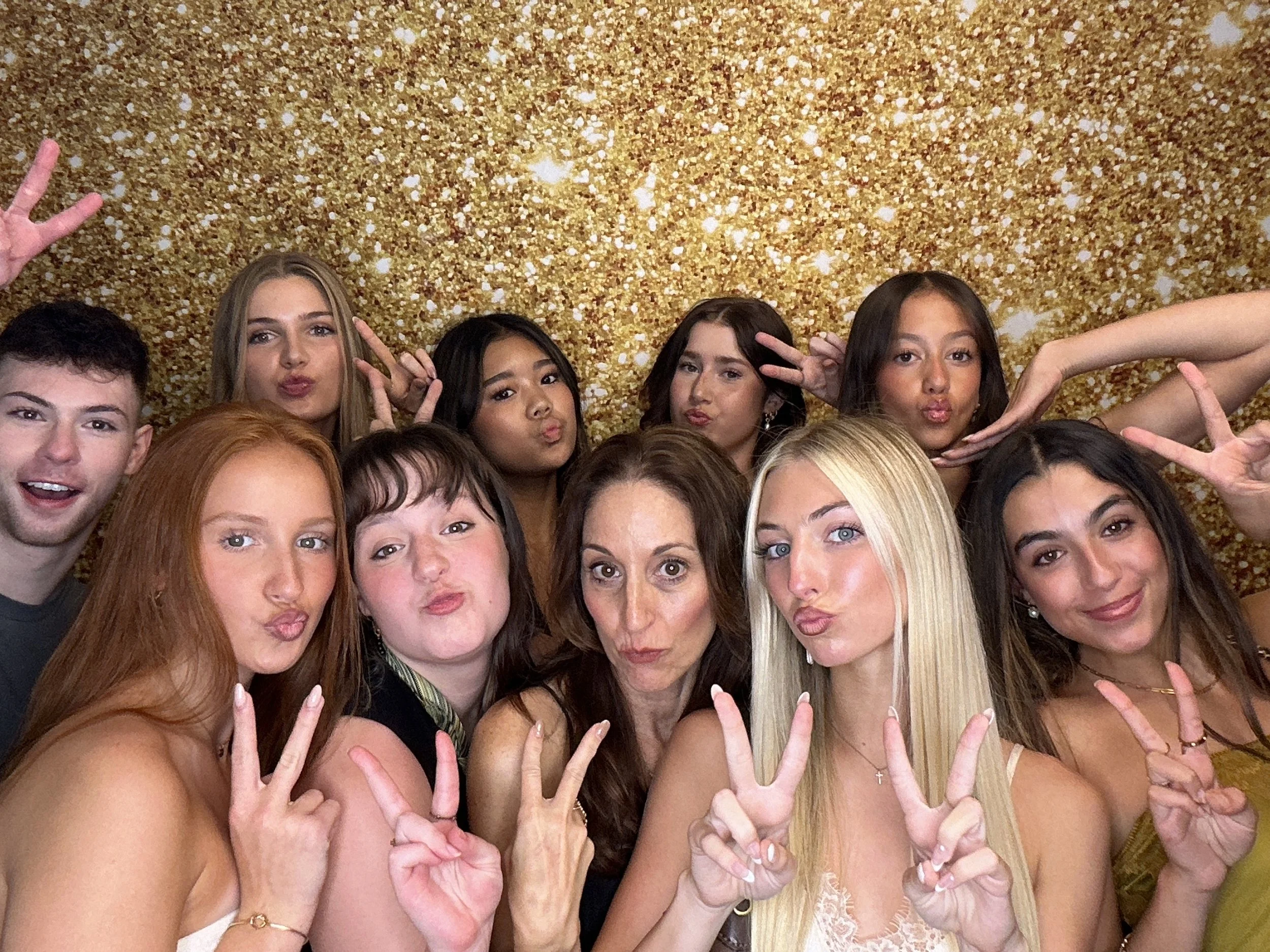 Guests posing together in front of a gold glitter backdrop at a celebration using a Pop & Pose Photo Booth in Lake Mary, Florida. Our Photo Booth rentals are perfect for weddings, birthday parties, corporate events, and school celebrations.