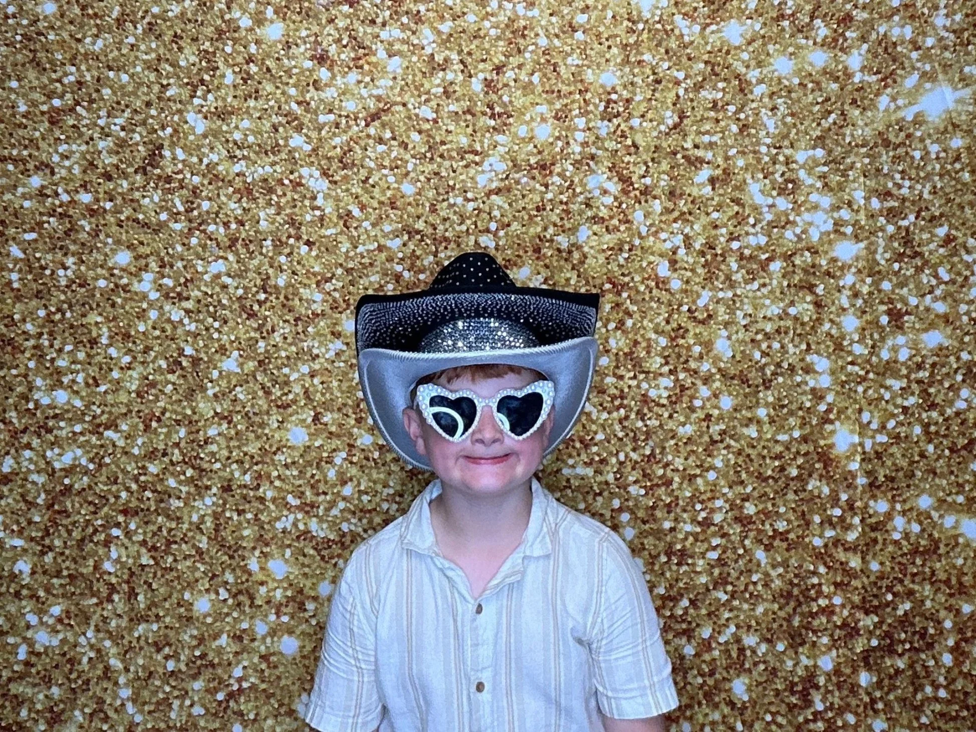 Young guest posing with fun Photo Booth props in front of a gold confetti backdrop during a birthday celebration. Pop & Pose Events provides modern Photo Booth rentals for birthdays and special events in Orlando, and throughout central Florida.