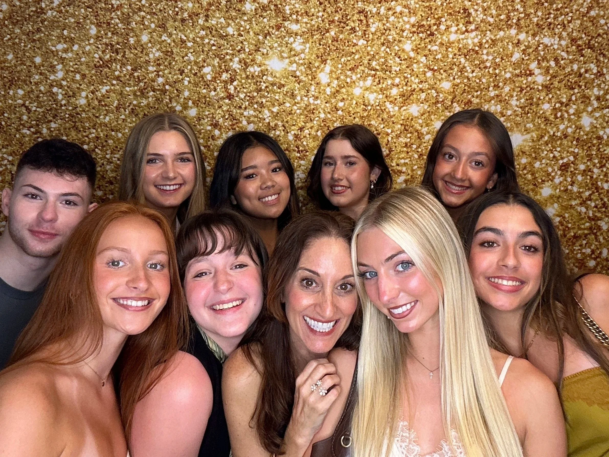 Guests enjoying a Pop & Pose Events Photo Booth at an end of year gala in Lake Mary, Florida. Guests are posing in front of a gold sparkly backdrop.
