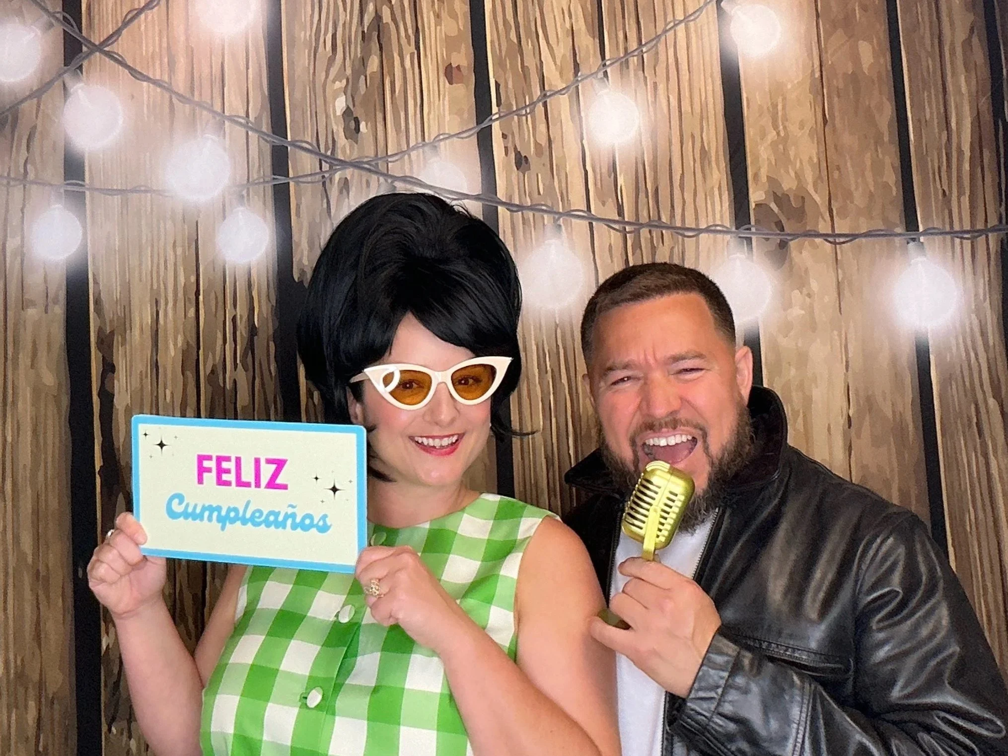 Guests celebrating a birthday with fun Photo Booth props in front of a rustic wood backdrop with string lights. Pop & Pose Events offers Photo Booth rentals for birthday parties, cultural celebrations, and private events throughout Sanford & Orlando.