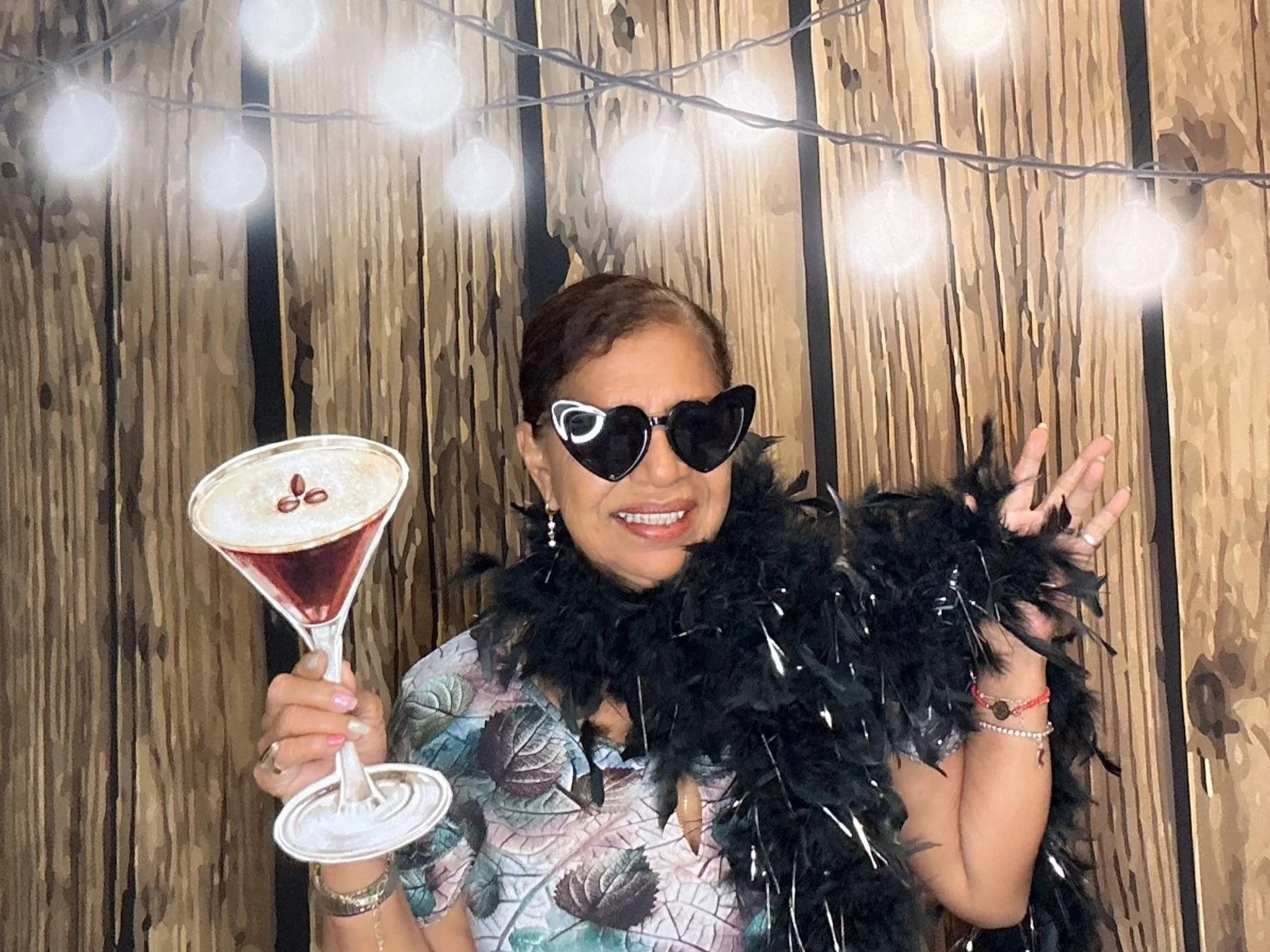Guests posing with Photo Booth props in front of a rustic wood backdrop with string lights at a celebration. Pop & Pose Events offers premium Photo Booth rentals for weddings, birthdays, and corporate events in Winter Springs, Oviedo, and Orlando.