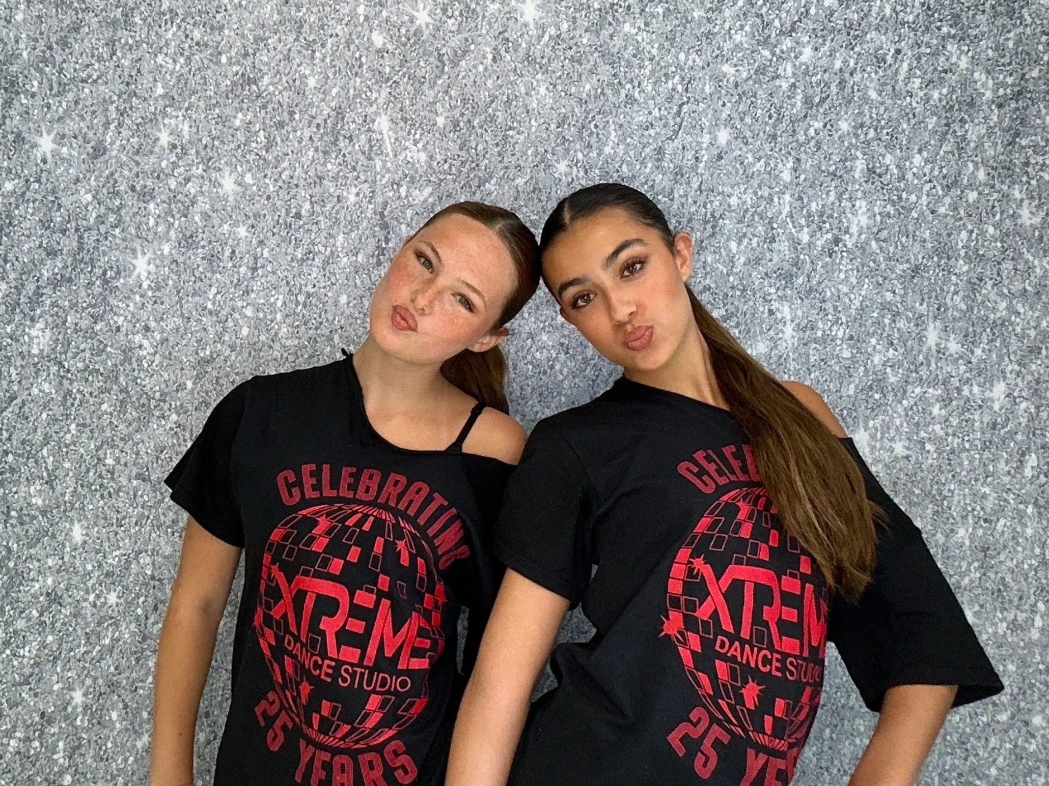 Dance studio students celebrating at a recital with a Pop & Pose Photo Booth and silver shimmer backdrop. We provide Photo Booth rentals for dance recitals, school events, competitions, and performances across Central Florida.