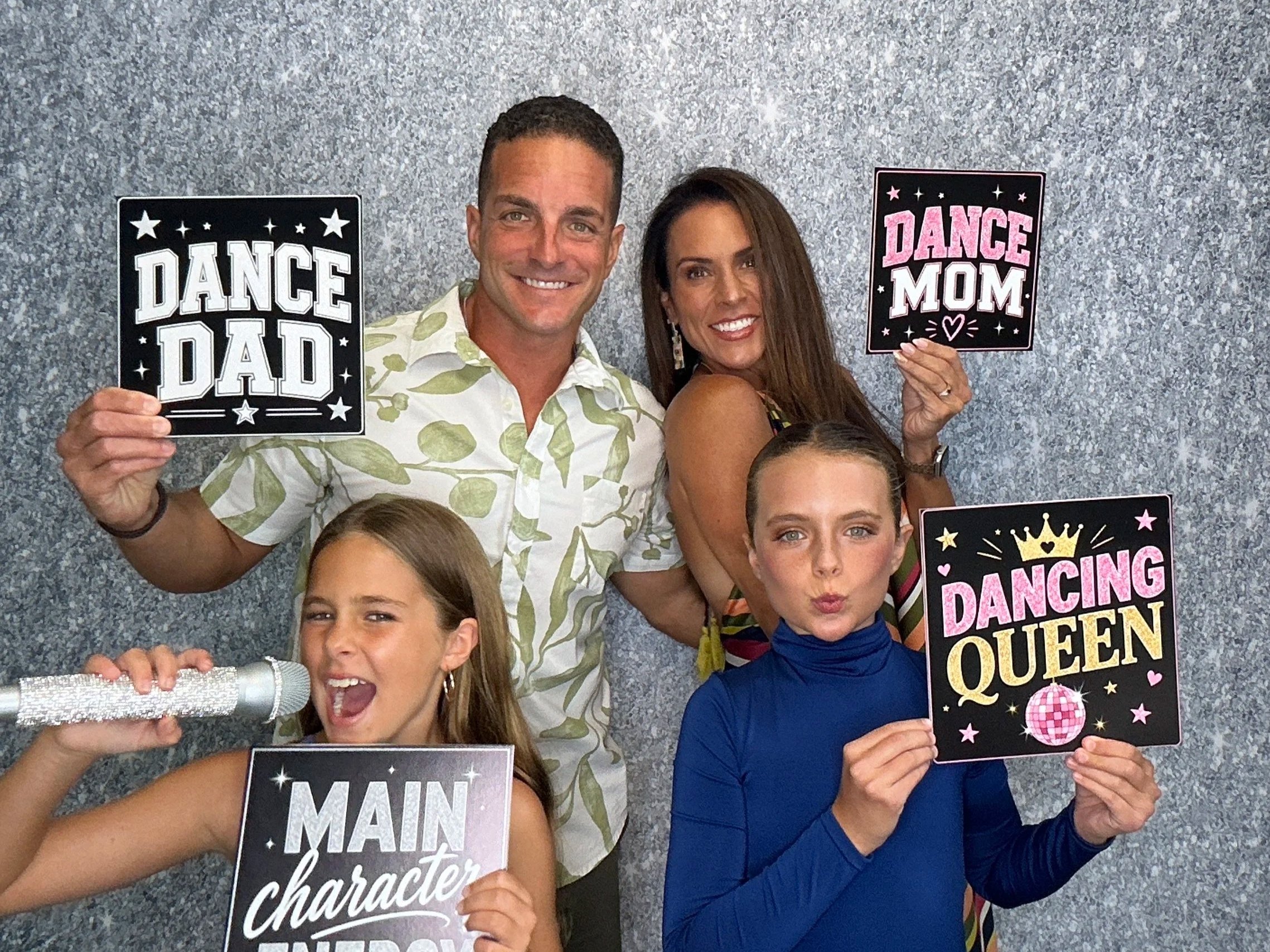 Families enjoying an Orlando Photo Booth rental at a dance recital, posing with custom signs and themed props.