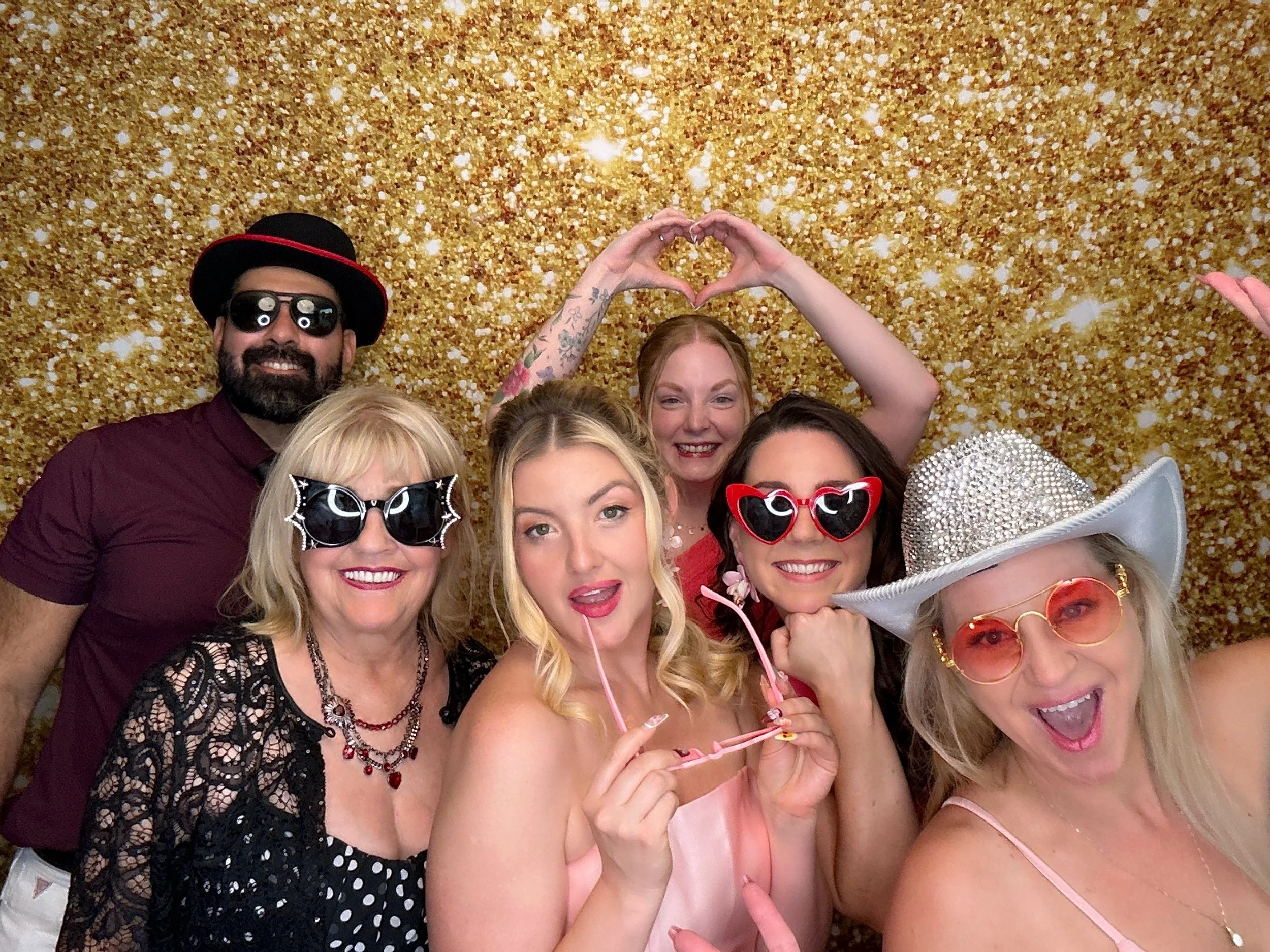 Friends posing with fun party props at an Orlando Photo Booth rental featuring a gold glitter backdrop.