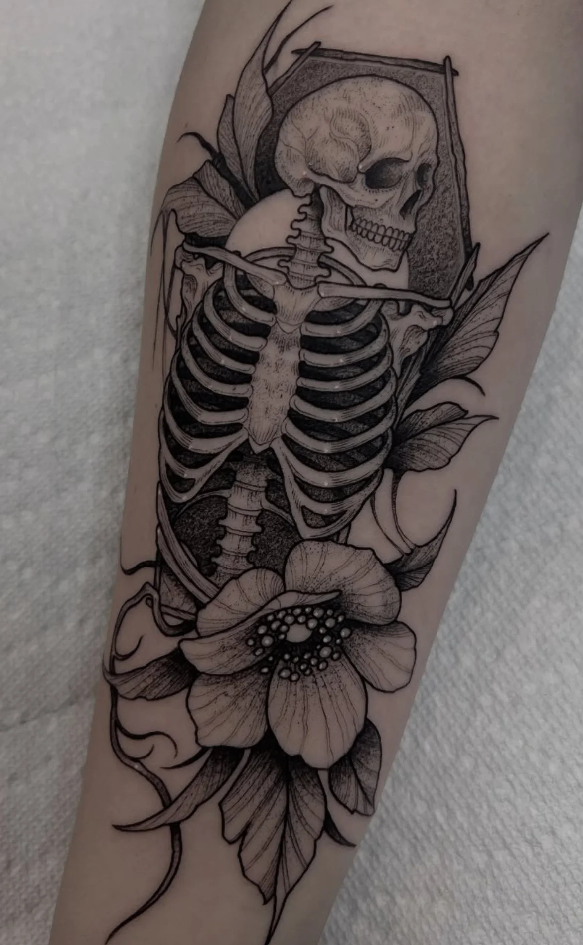 Blackwork tattoo Rochester NY Skeleton coffin floral bone 