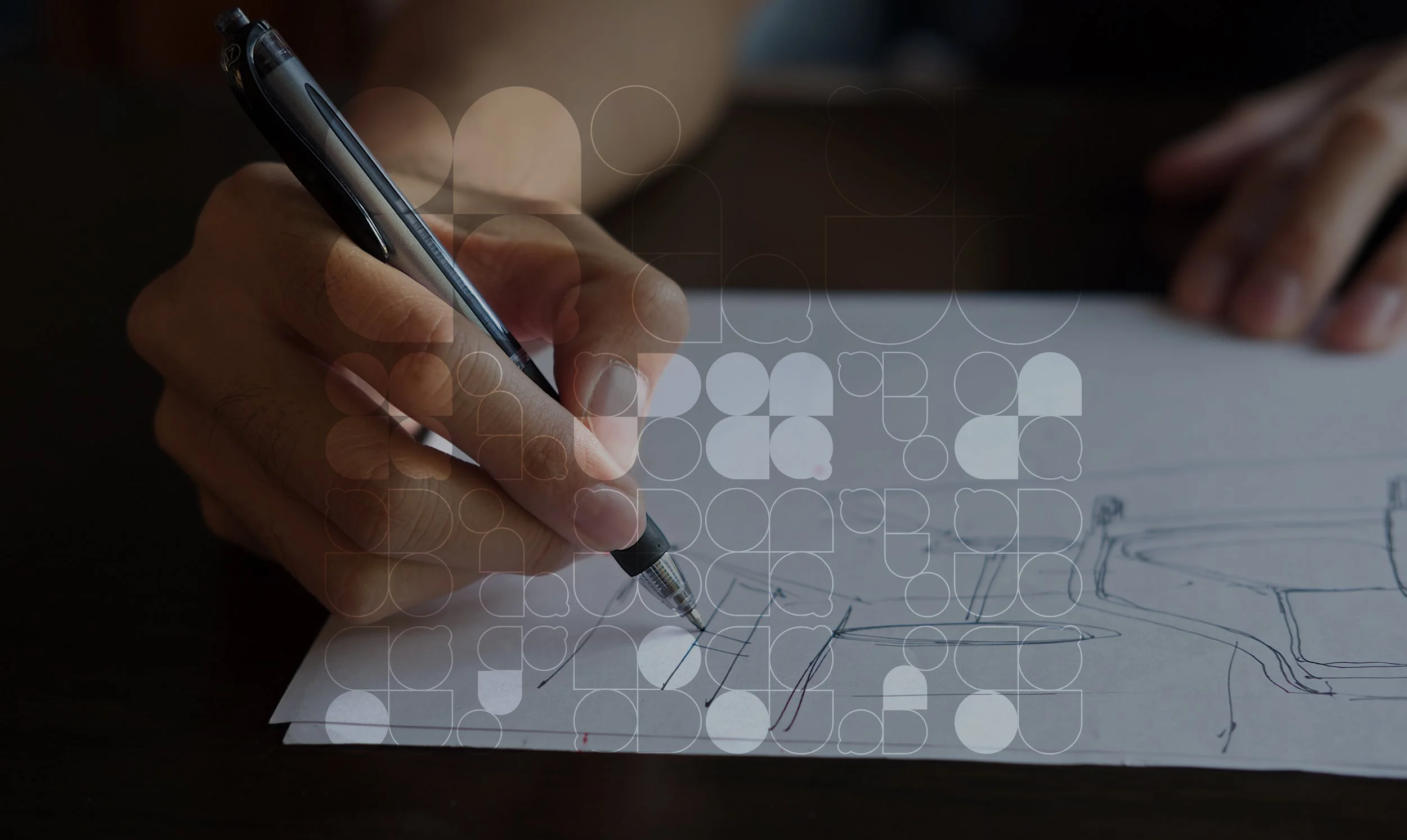 Persona dibujando con bolígrafo sobre papel con diseño de objetos geométricos.