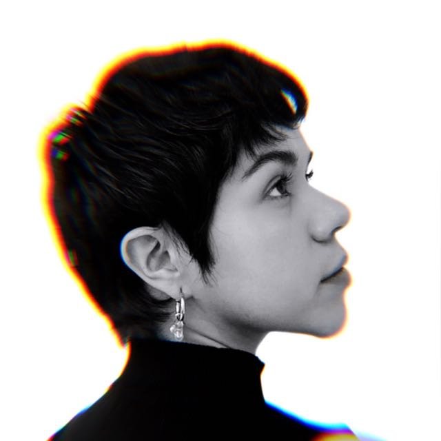 Retrato en blanco y negro de persona con peinado corto, mirando hacia arriba. Fondo blanco, efecto de luz colorido alrededor del cabello.