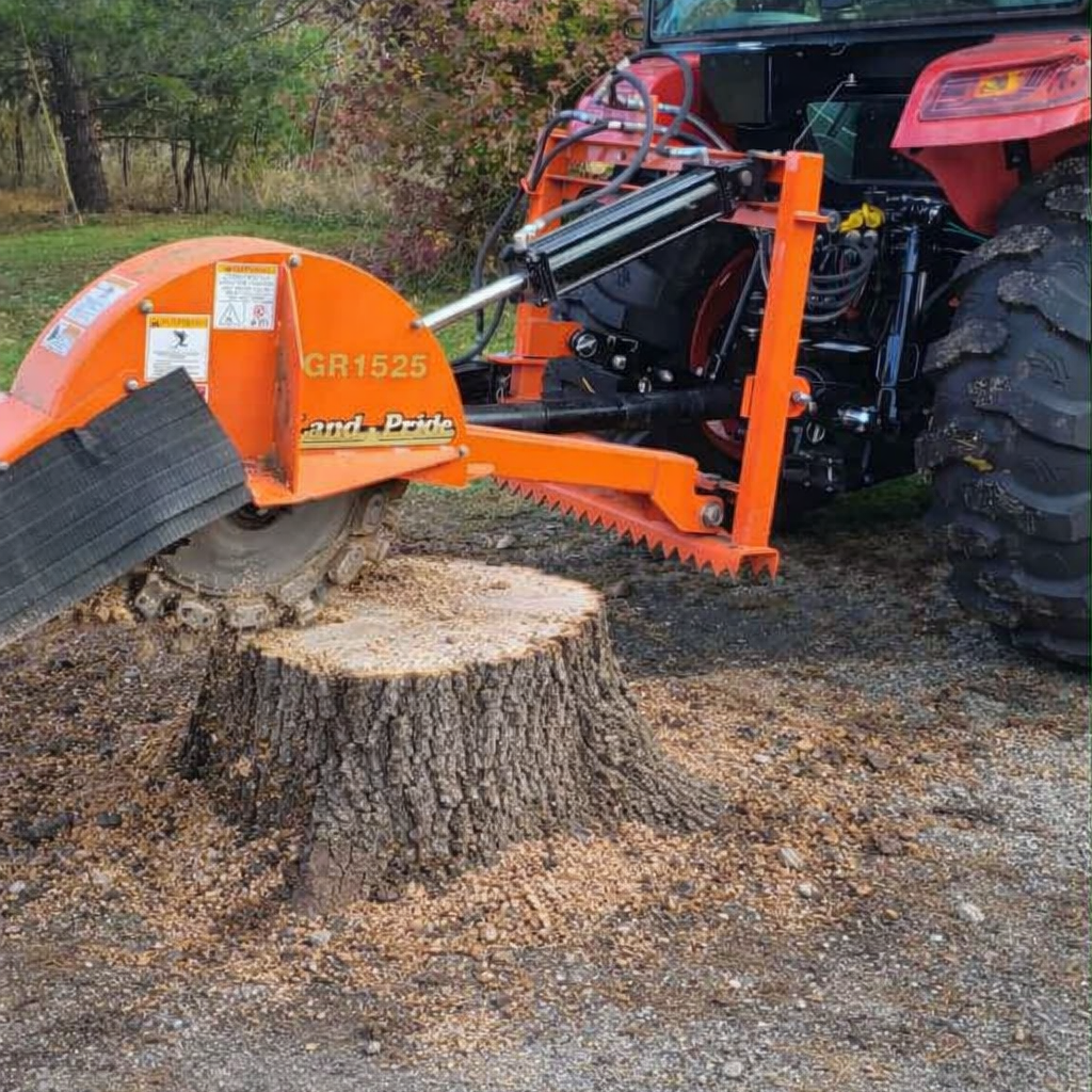 A wood cutting machine attached to a tractor cutting a large tree trunk into logs or firewood outdoors.