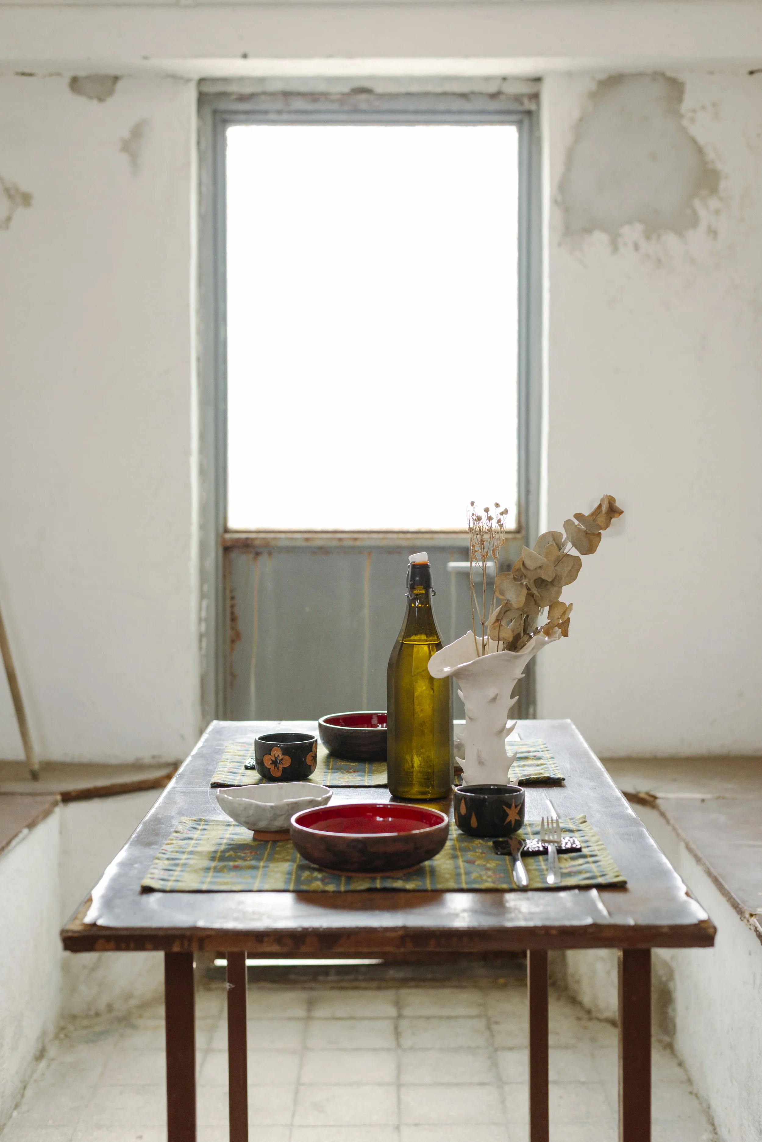 Tavola apparecchiata con ceramiche artigianali uniche e scultoree.