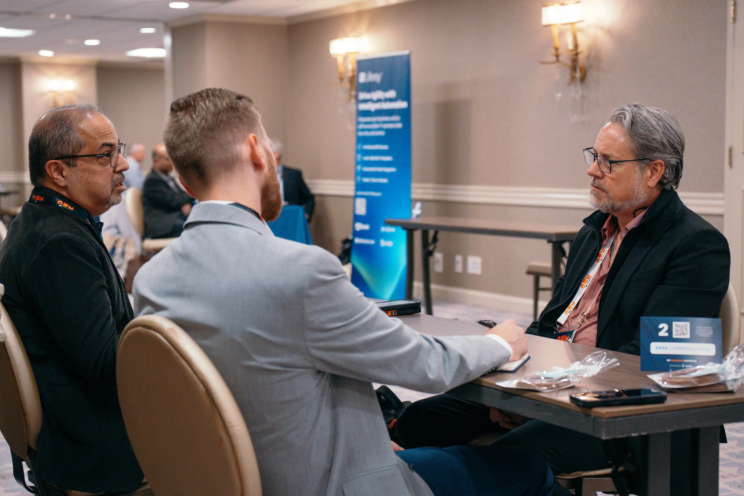 Conference attendee engaging with a sponsor at an executive business summit at the Adolphus Hotel in Dallas.