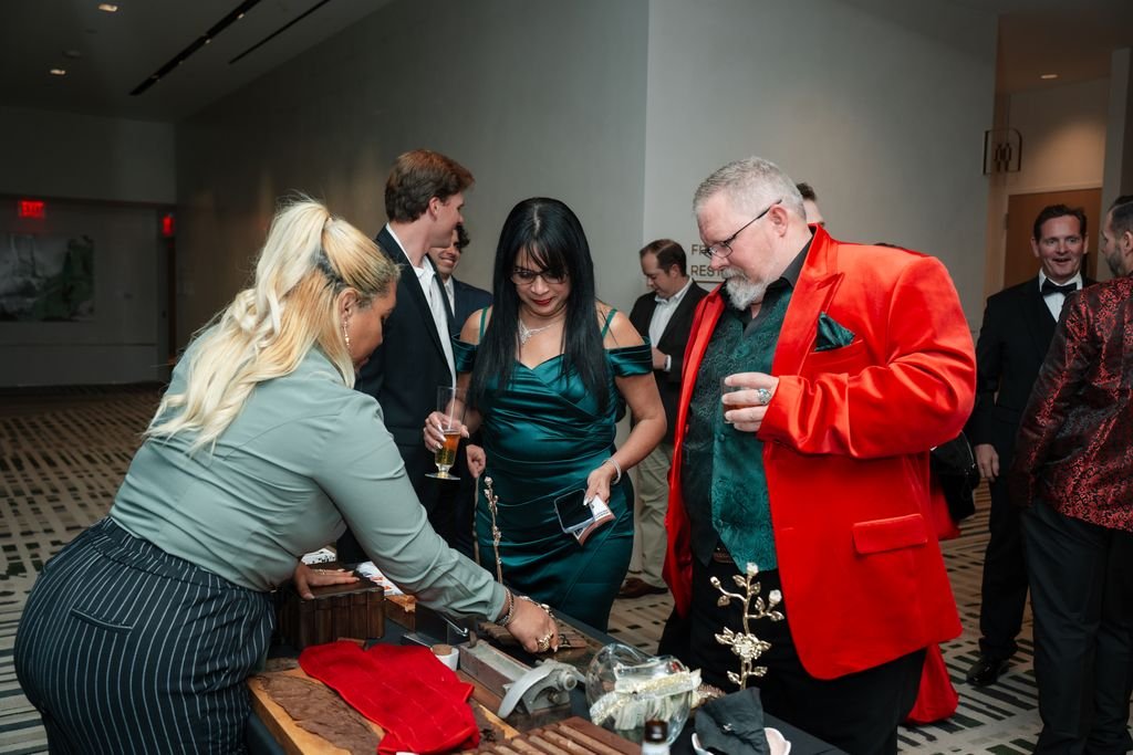 People at a reception or social gathering, with individuals serving themselves food or drinks at a table.