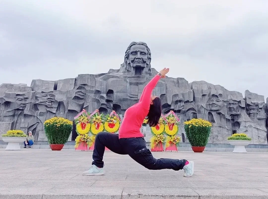 A woman in pink sweater and black pants doing a yoga pose in front of the Lincoln Memorial in Washington, D.C., decorated with flower arrangements.