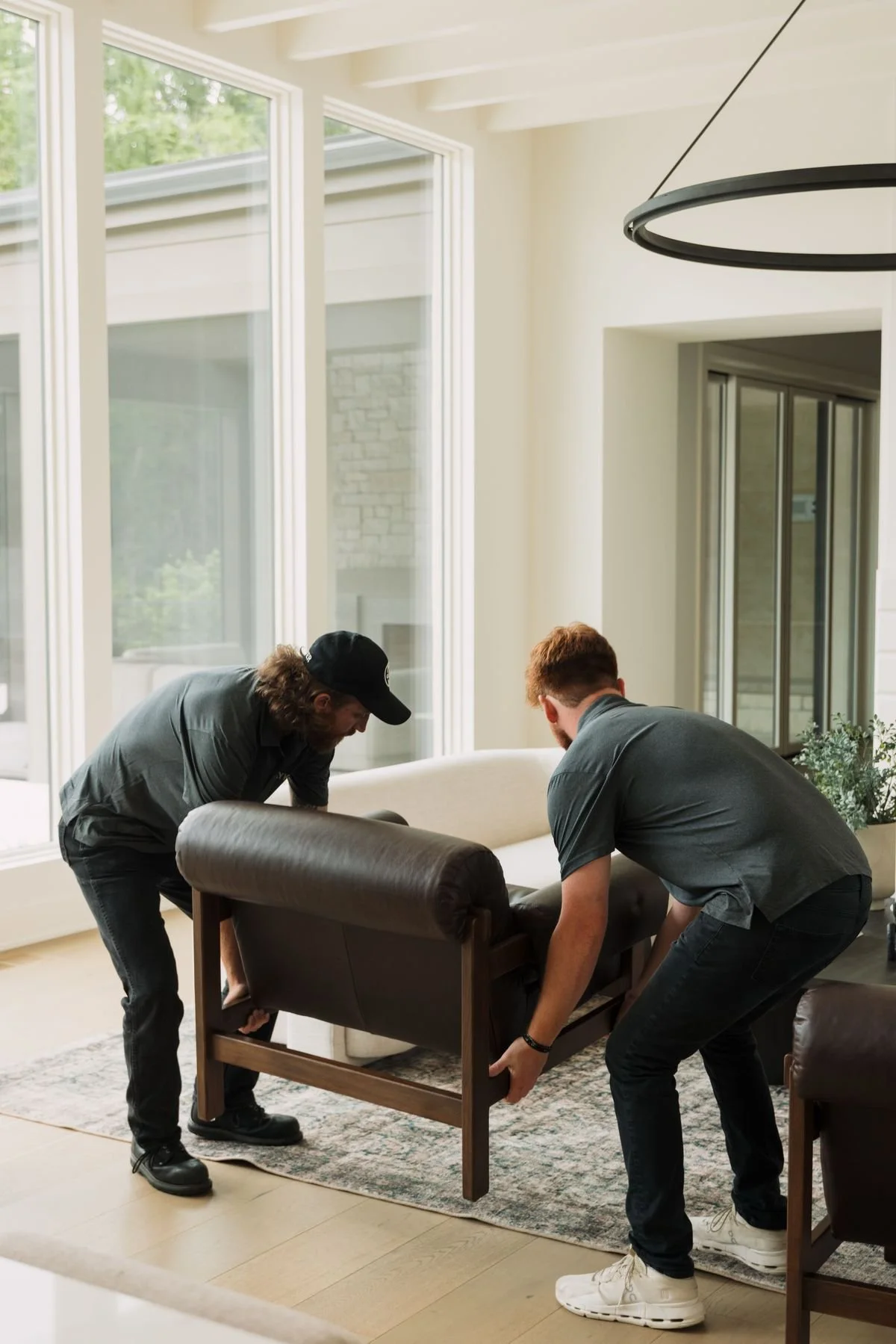 Moving armchair into place during home furnishing install in bright living room.