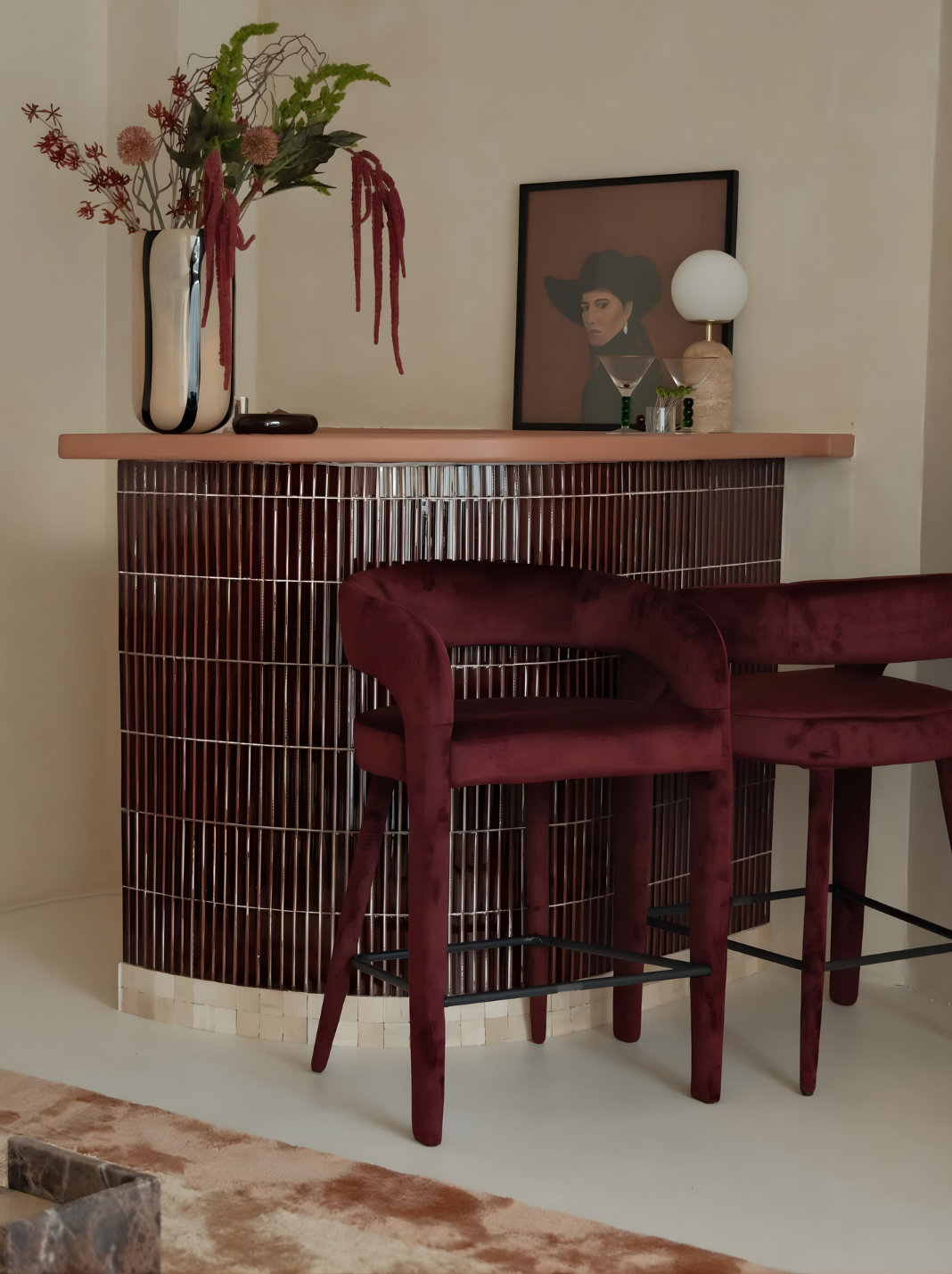 Statement home bar with burgundy stools, curved joinery and layered entertaining style.