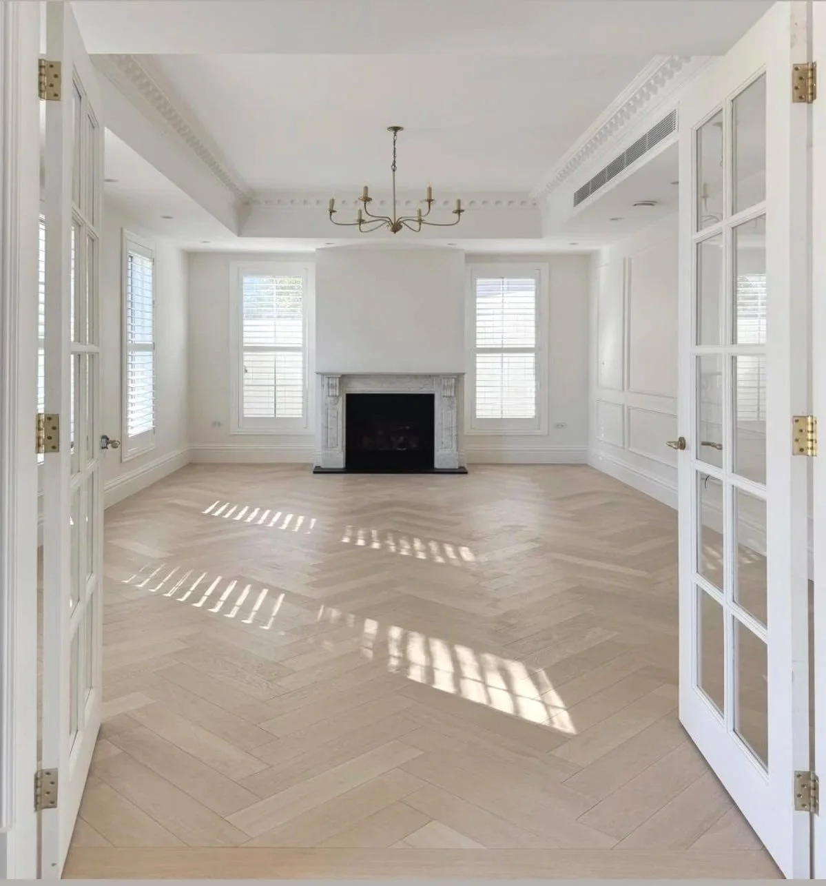 Empty living room with fireplace, French doors and natural light, ready for furnishing.