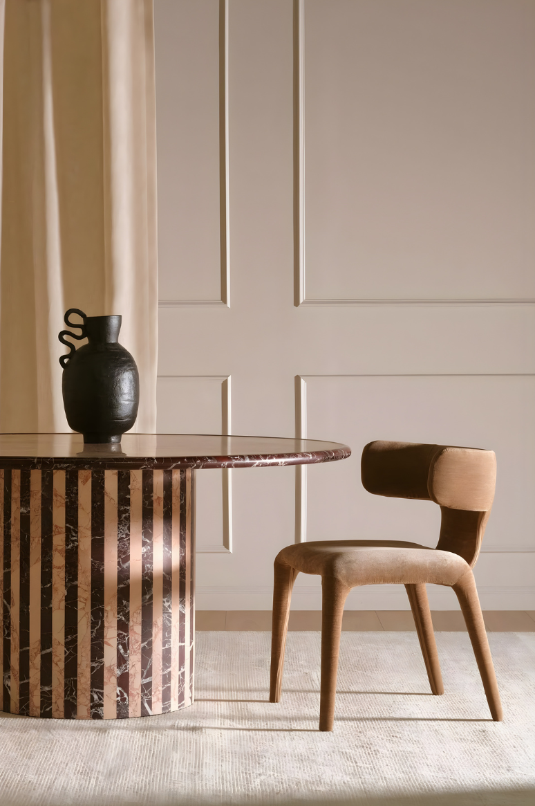 Dining corner with marble table, curved chair and soft neutral interior styling.