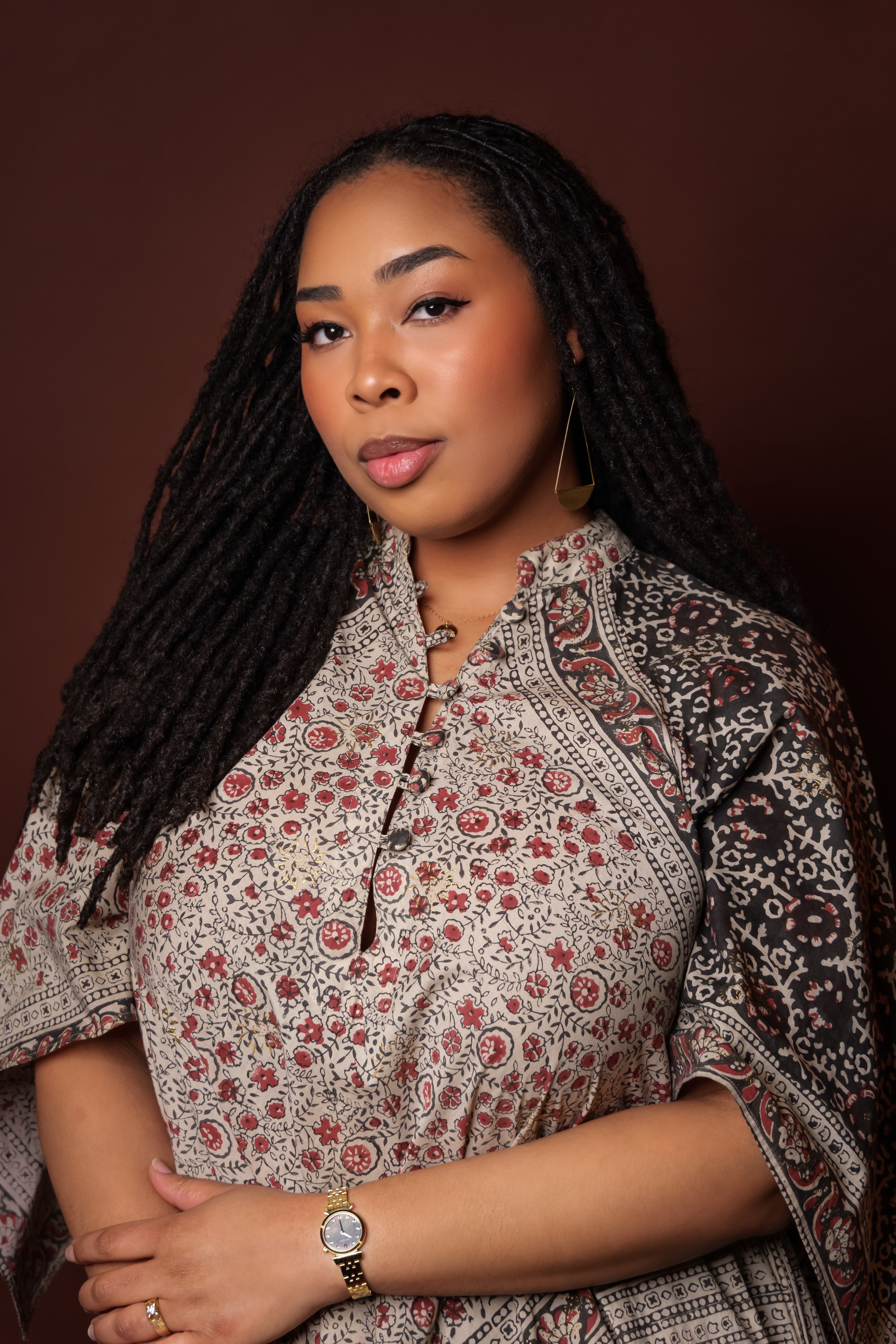 Chelsea Gayden, fiction author, smiling softly in a floral print dress.