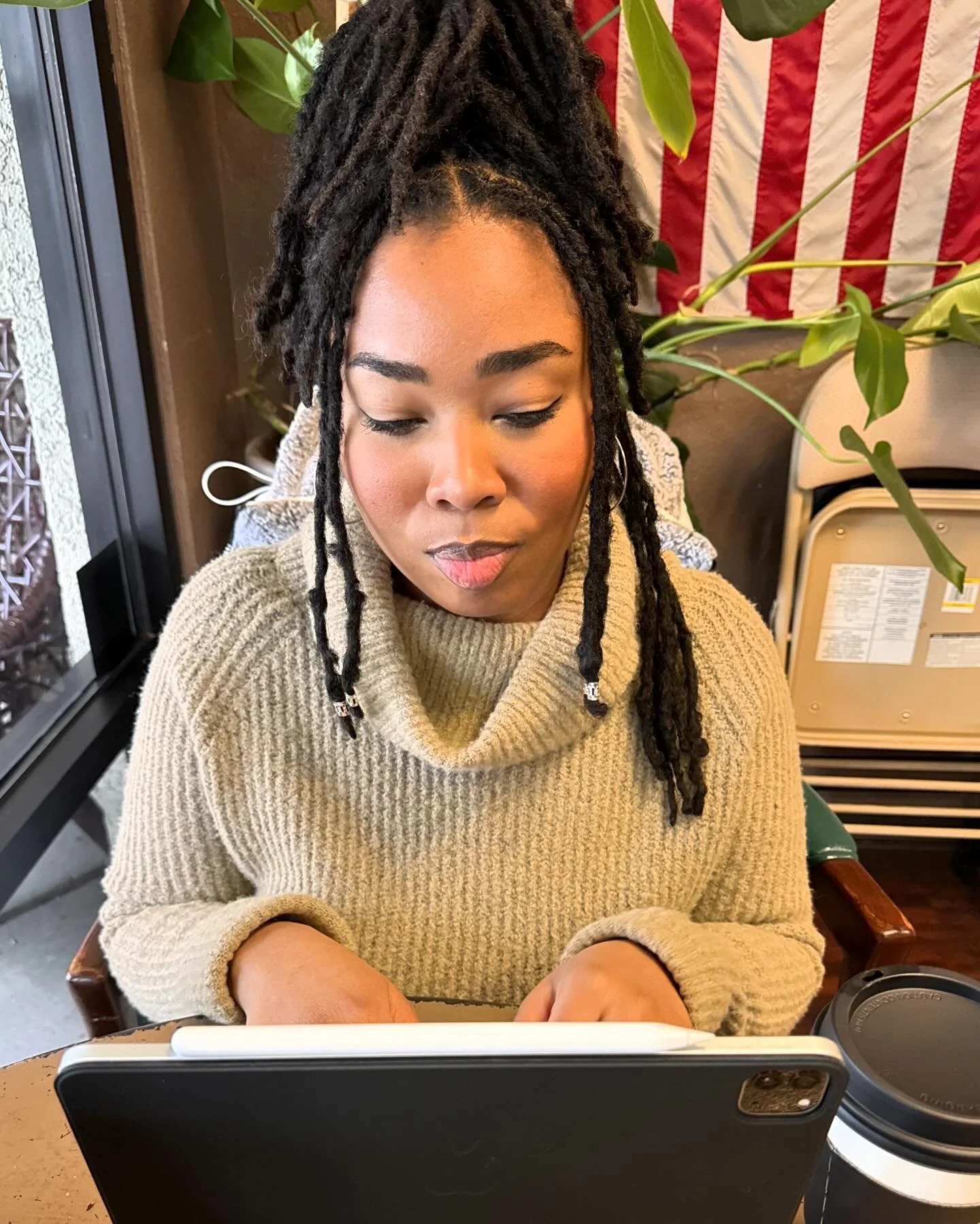 Chelsea Gayden, fiction author, tying and looking down at a screen in a beige sweater.