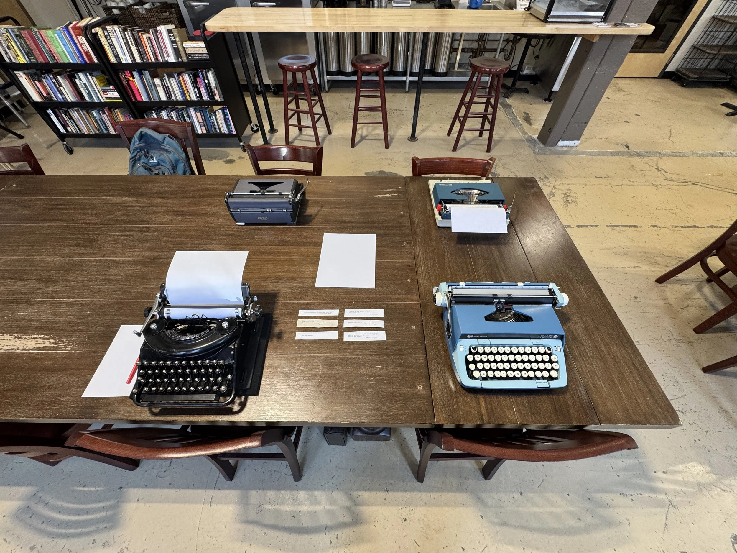 Four typewriters set out on a large table for attendees to try at the Tappa Tappa typewriter meetup.