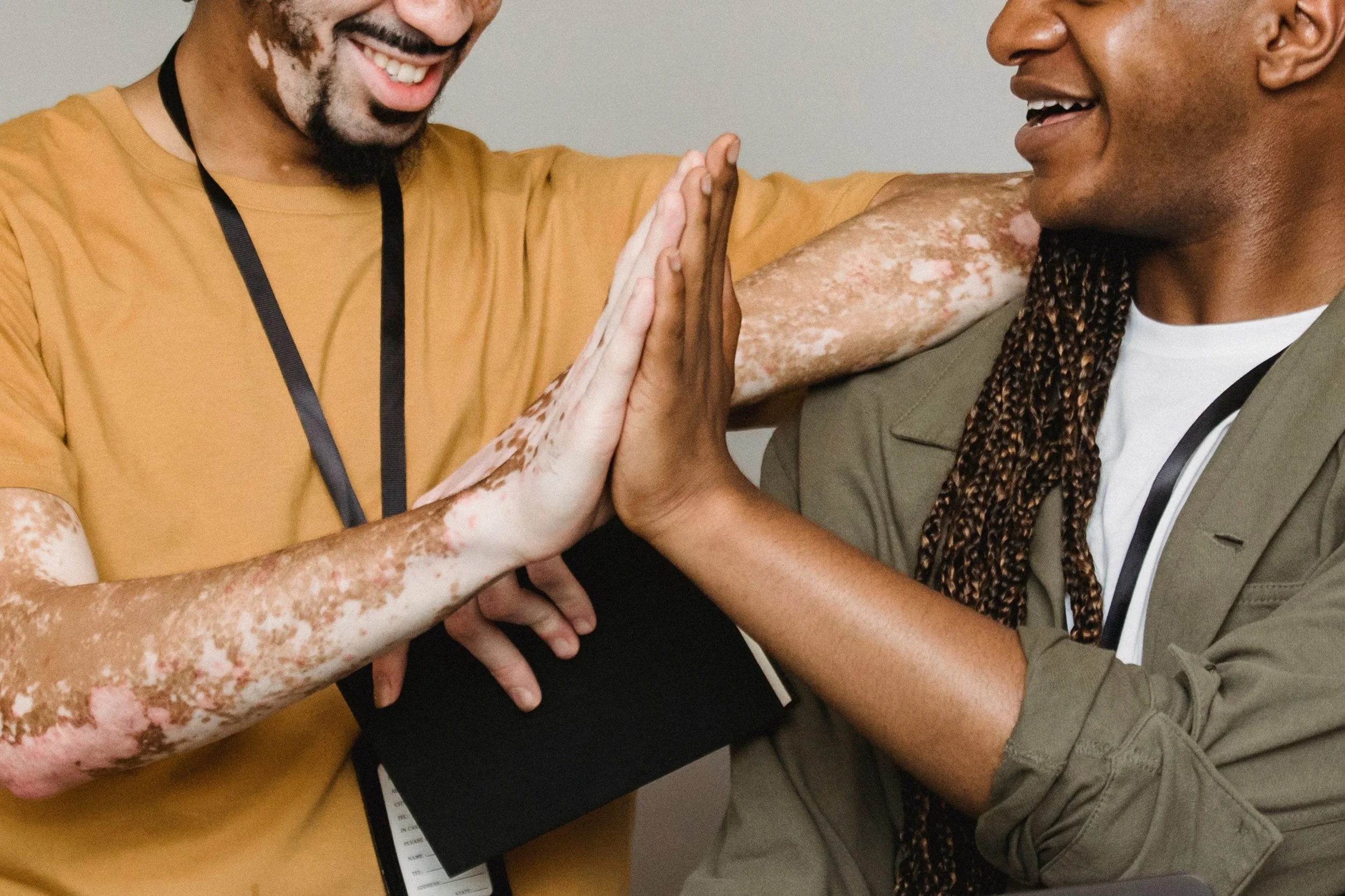 A biracial  same-sex couple hi-fiving each other.