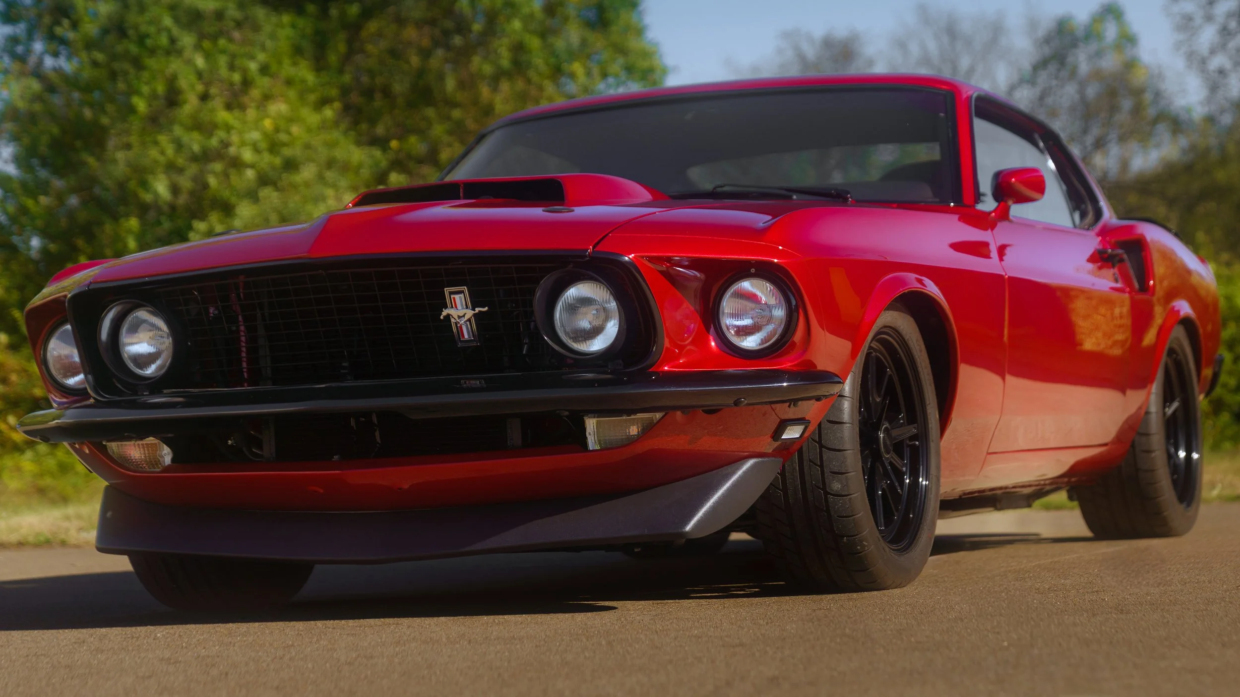 front driver side quarter shot of red 1969 coyote swap mustang different angle