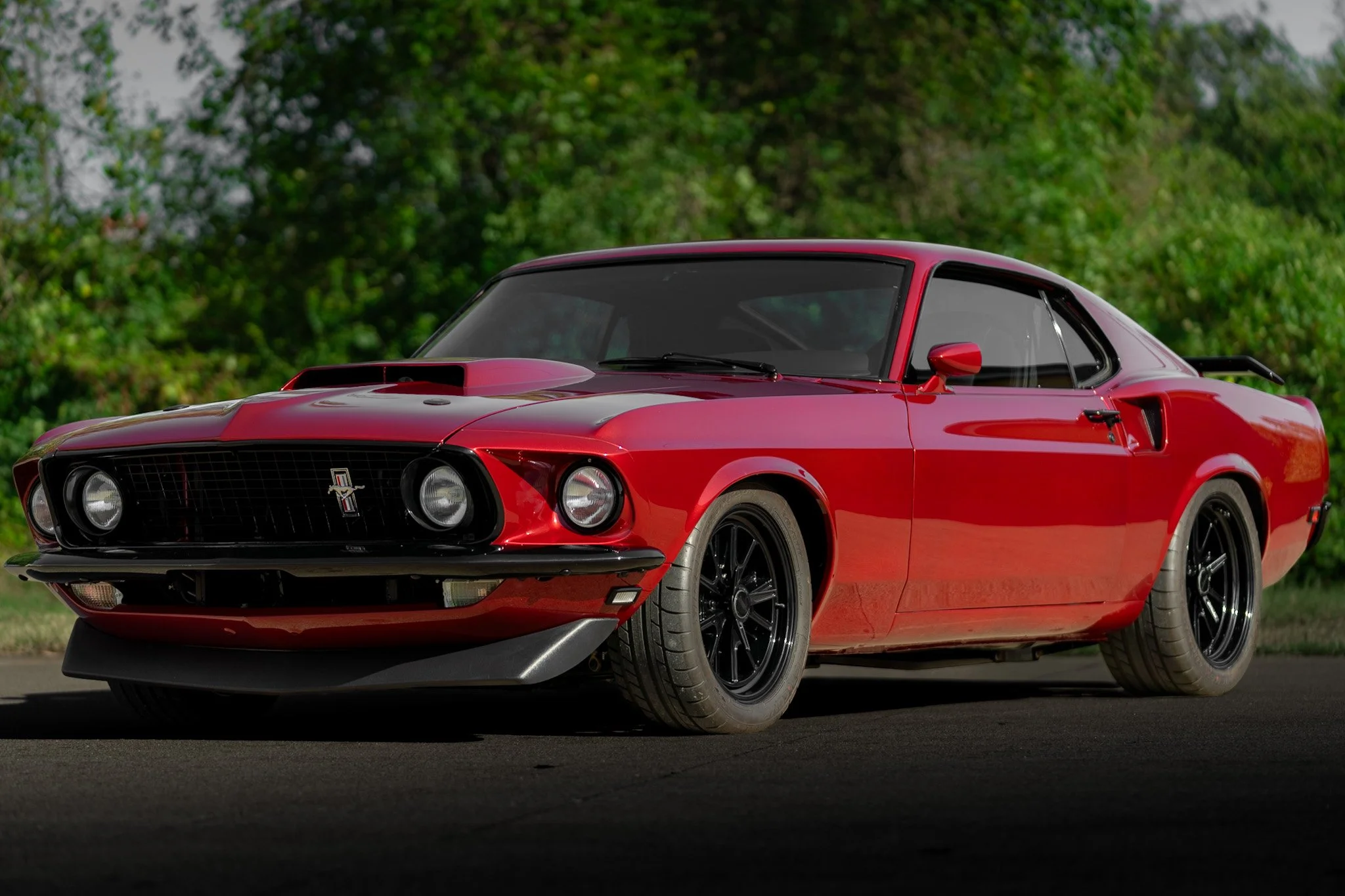 front drivers quarter shot of red 1969 coyote swap mustang different angle
