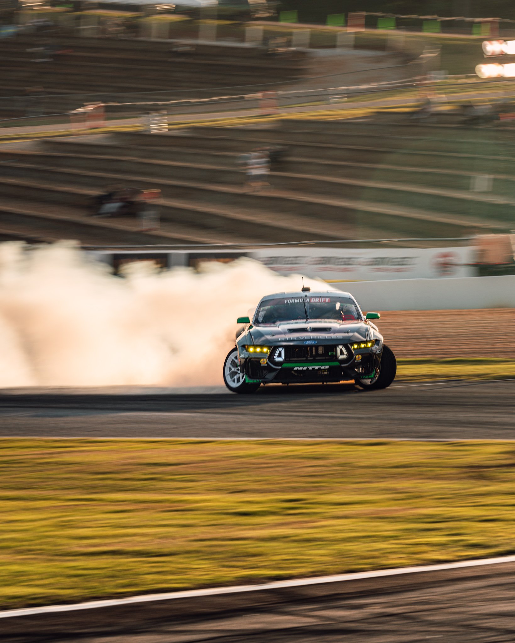 A race car speeding on a track, creating a trail of smoke behind it, with blurred background indicating high speed.