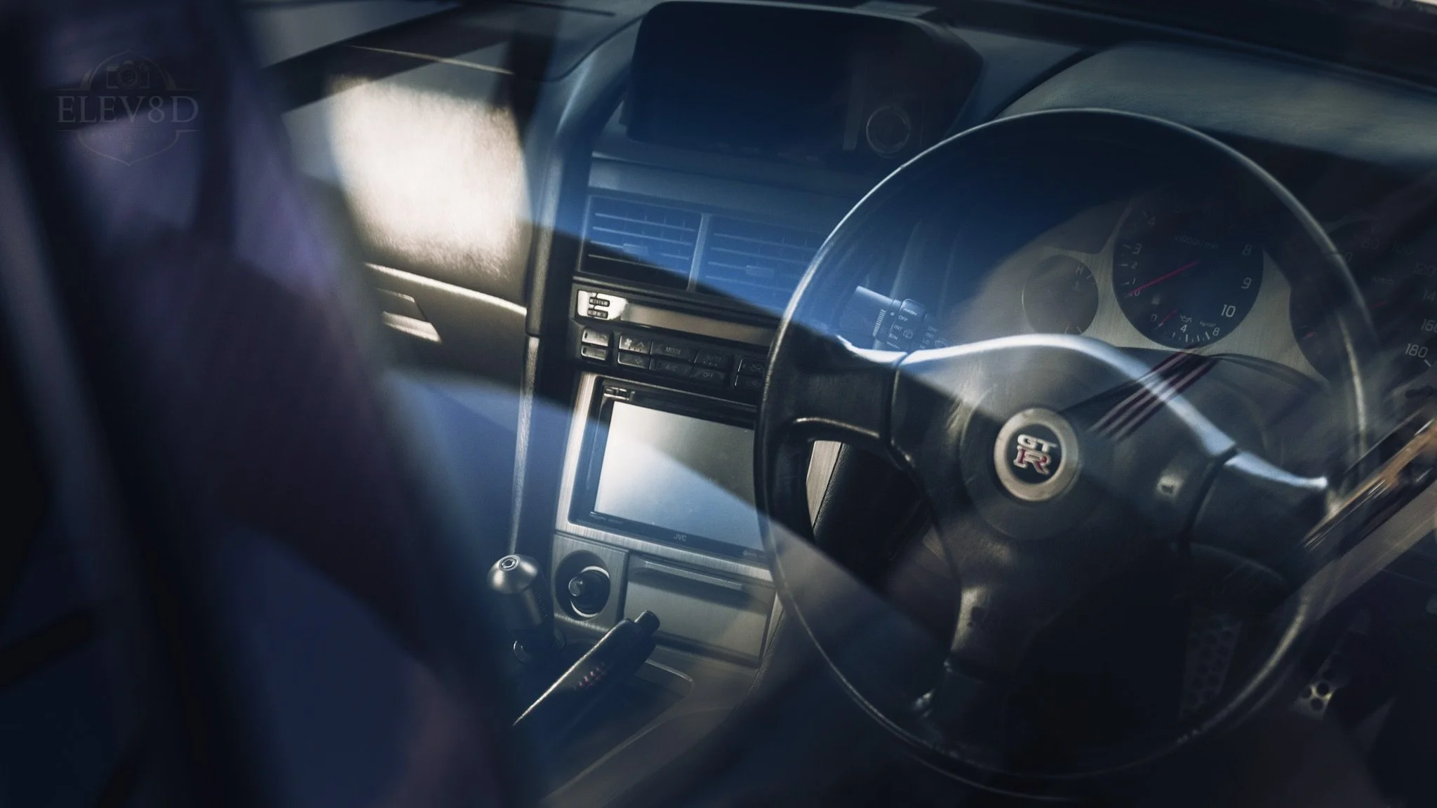 Interior view of a car dashboard featuring a steering wheel with a GT-R badge, speedometer, and various controls.