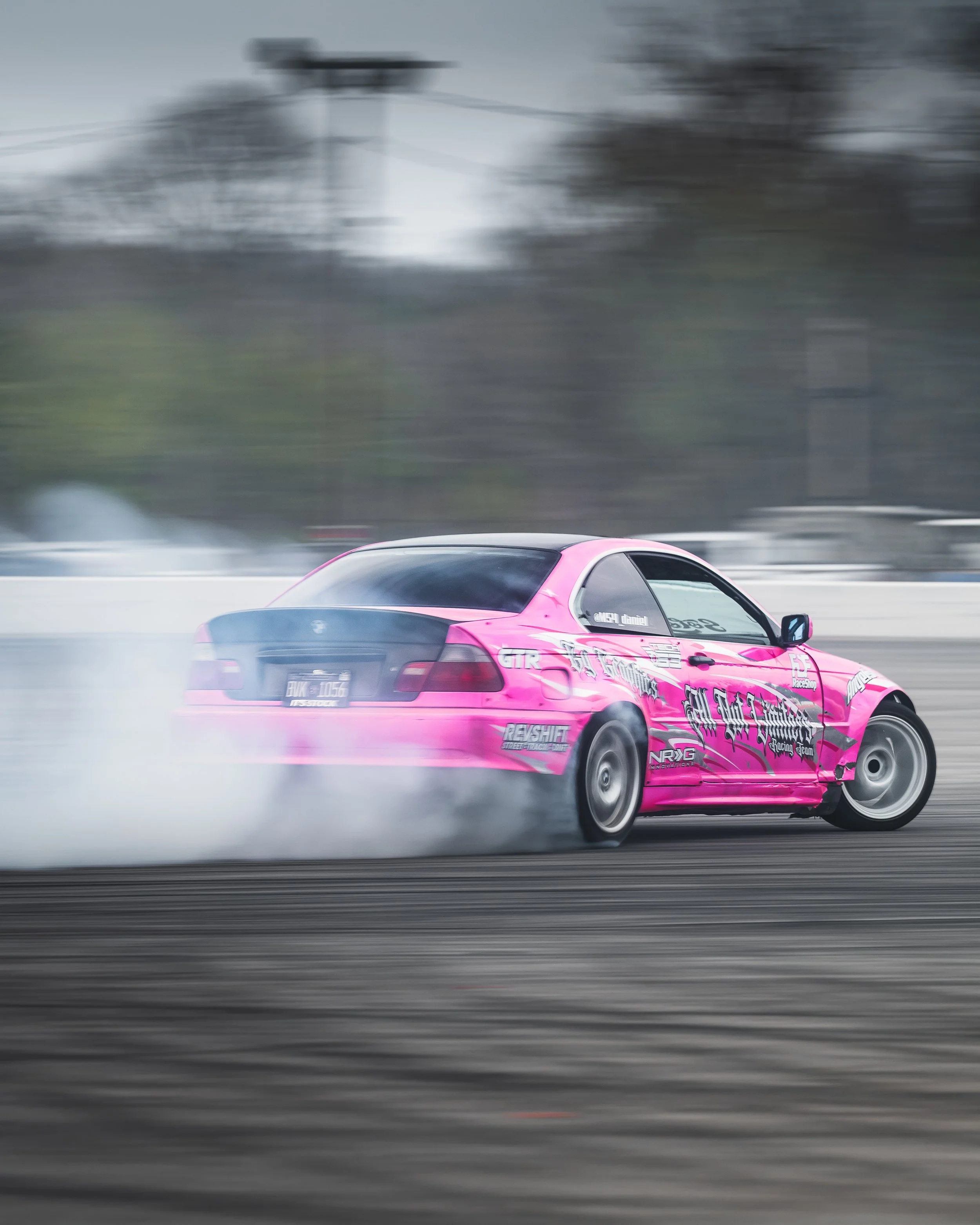 A pink race car drifting on a track, creating smoke from the tires.