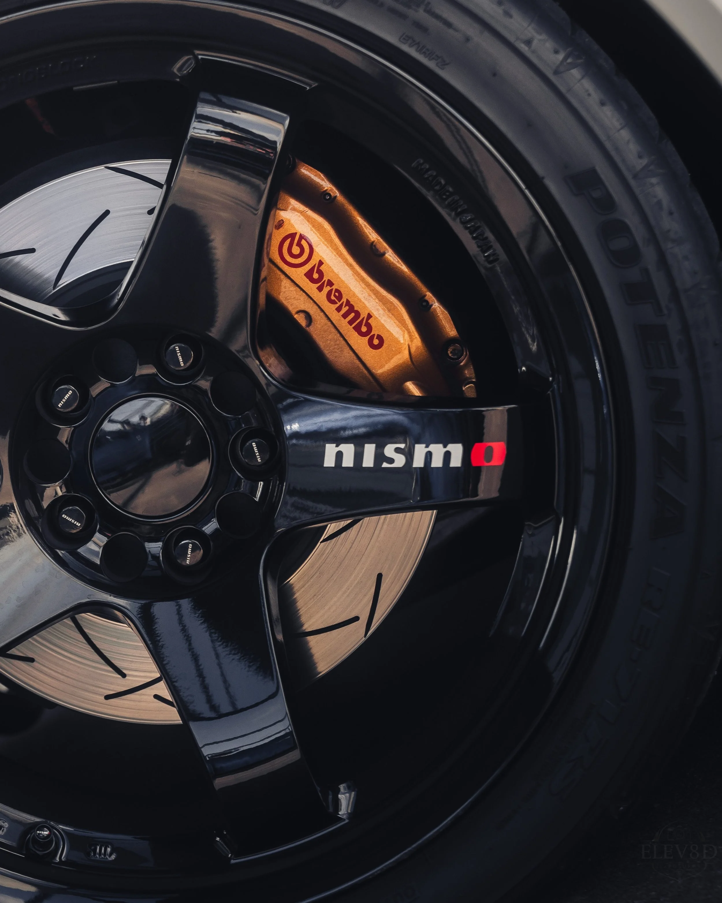 Close-up of a car wheel with a black rim, gold brake caliper with the Brembo logo, and a brake disc, featuring a low-profile tire with the brand 'Potenza'.