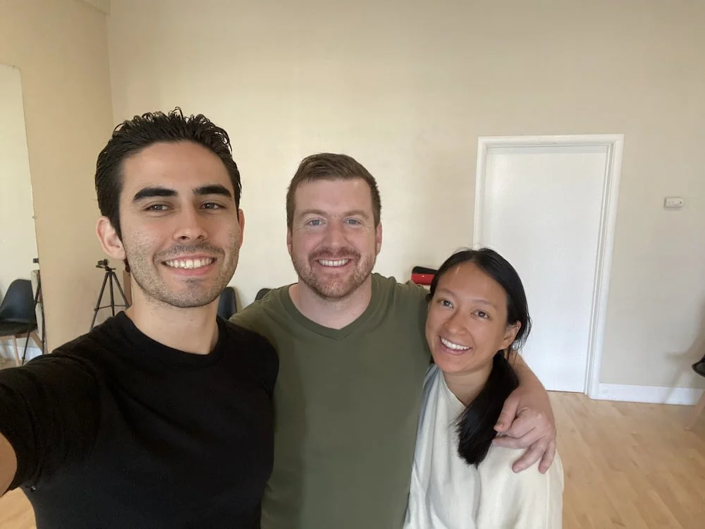 Richard, a San Francisco-based wedding dance instructor, smiling and taking a selfie in a dance studio with one of his wedding dance couples.