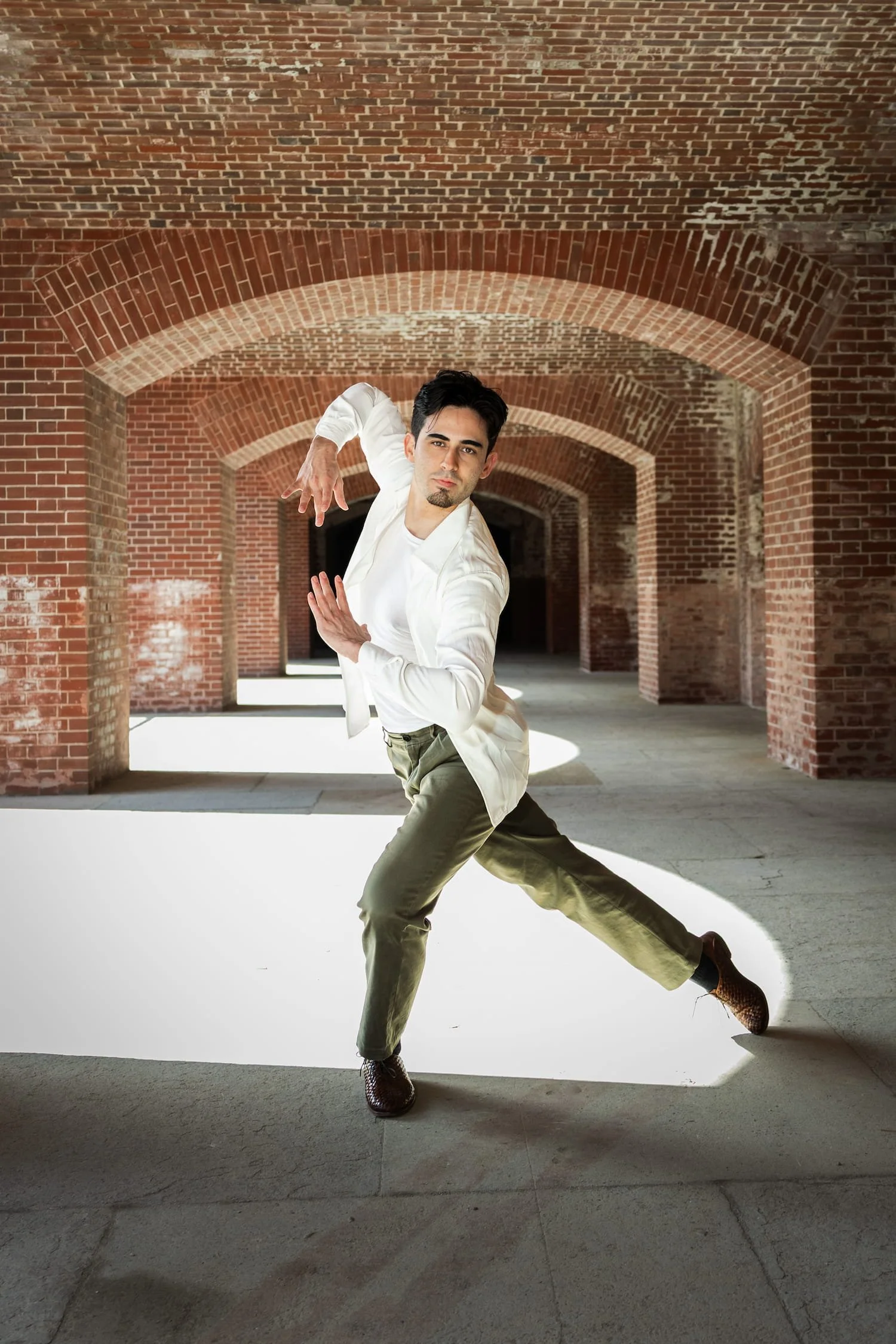 Richard Hornor, ballroom dance instructor based in San Francisco, striking a dance pose in a brick tunnel.