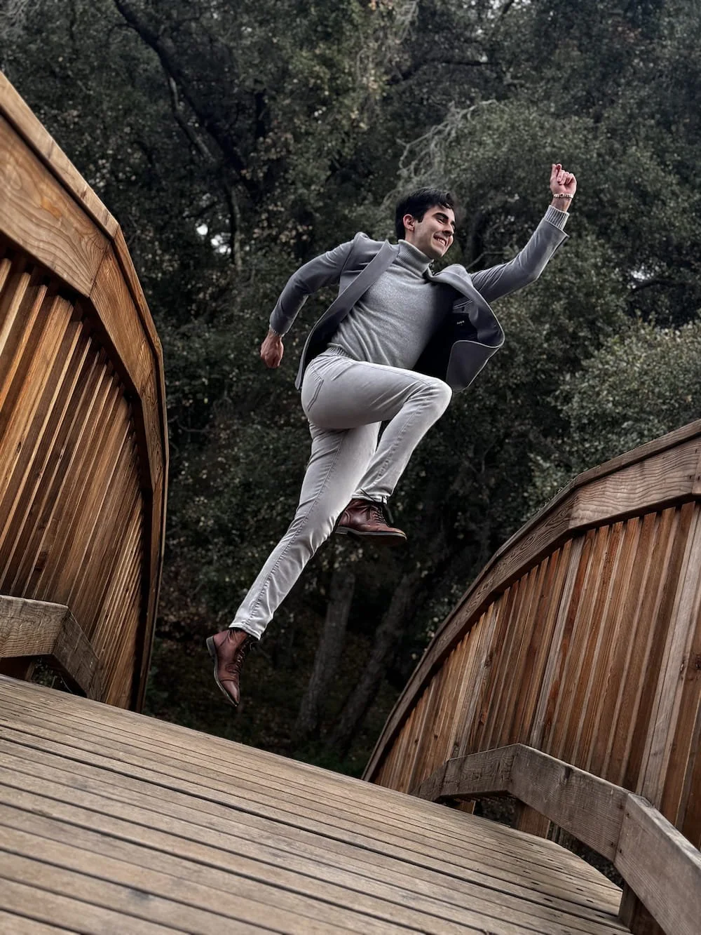 Richard, a San Francisco-based wedding dance instructor, dancing on a wooden bridge outdoors surrounded by trees.