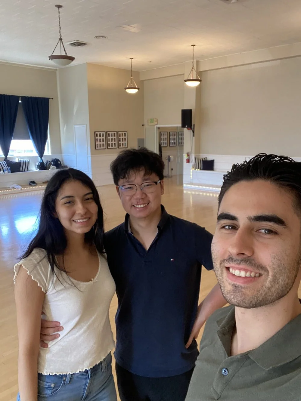 Richard, a San Francisco-based wedding dance instructor, smiling and taking a selfie in a dance studio with one of his wedding dance couples.