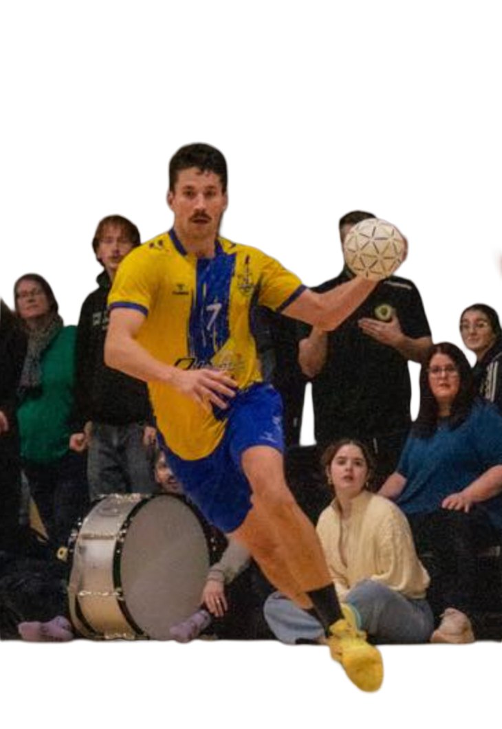 A man in a yellow and blue sports uniform is holding a ball and appears to be in motion. He is surrounded by a group of spectators, some sitting and some standing, with a drum and a person in black behind him.