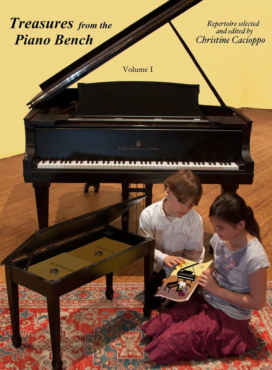 Two children, a boy and a girl, sitting on a patterned rug in front of a grand piano with an open book, looking at illustrations of a piano and a child playing it.